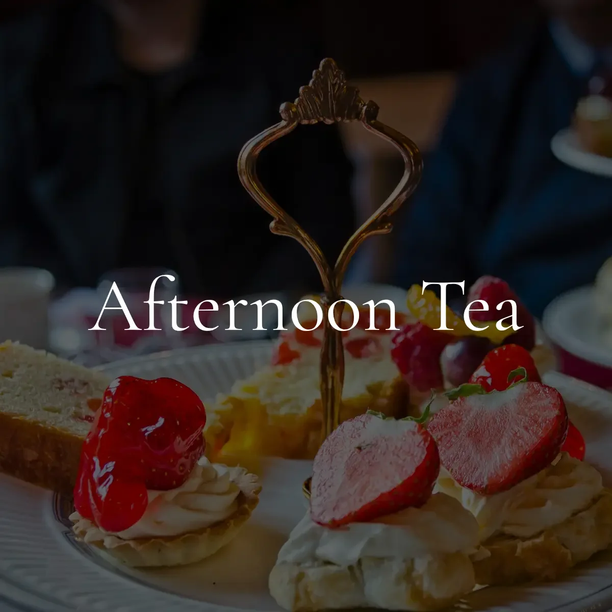 A plate of assorted pastries topped with strawberries, raspberries, and whipped cream, with a decorative metal fork and the text 'Afternoon Tea' overlaid.