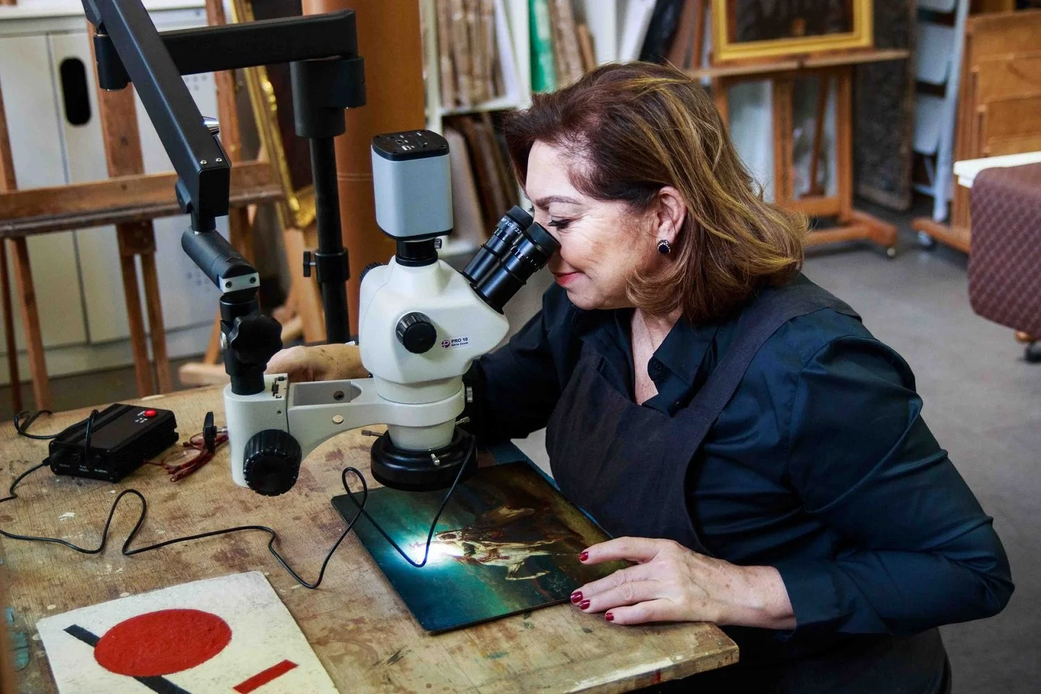 Deux femmes travaillent sur la restauration d'une peinture ancienne dans un atelier.