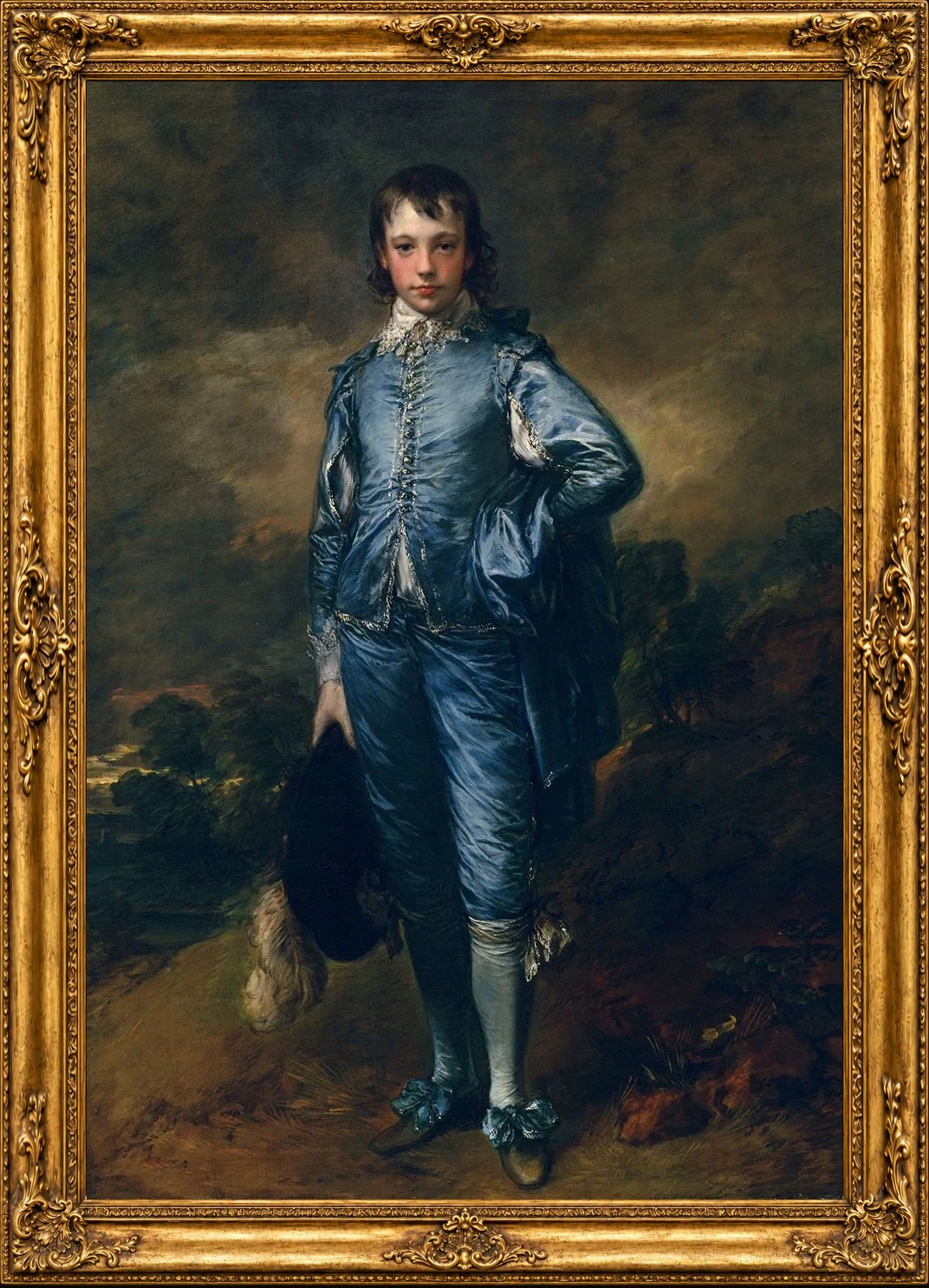 A young boy dressed in 18th-century attire, standing outdoors with hands on hips, holding a hat with one hand, in a landscape setting with trees and a cloudy sky in the background, inside an ornate gold frame.