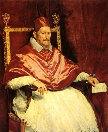 Painting of a regal man sitting on a throne, wearing a red robe, a tall hat, and holding a document, with a rich red background.