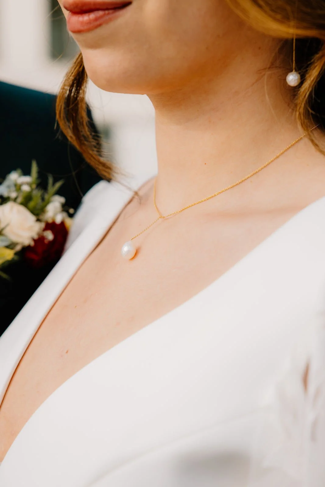 Nahaufnahme des Brautschmucks mit Perlenkette und Ohrring
