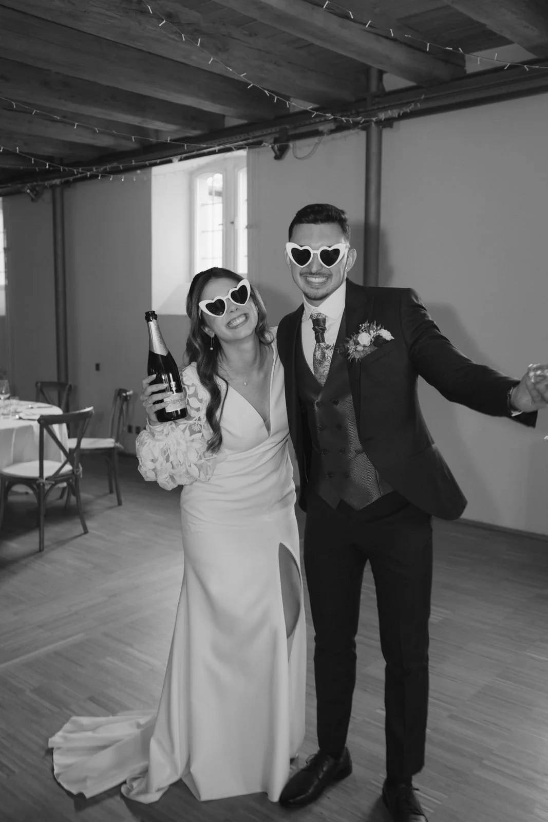 Ein lachendes Brautpaar in Anzügen und Brautkleid feiert sorgenlos auf ihrer Hochzeit