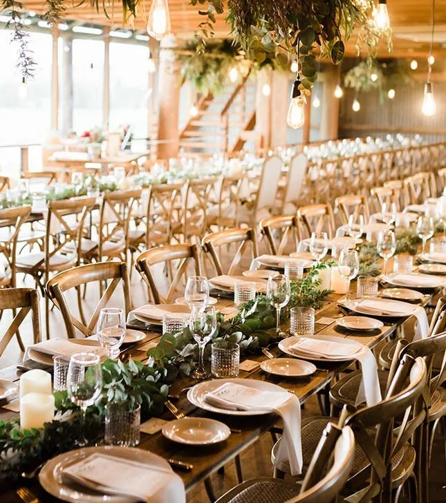 Festlich dekorierter Hochzeitssaal mit langem Tisch, Kerzen, Pflanzen und warmem Licht – stilvolle Hochzeitslocation nahe St. Gallen.