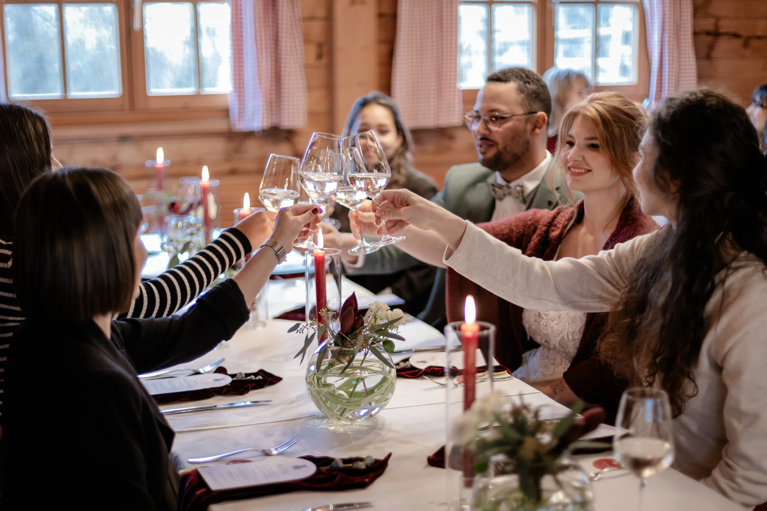 Fröhliche Hochzeitsgesellschaft die gemeinsam auf das Hochzeitspaar anstoßt bei einer Winterhochzeit