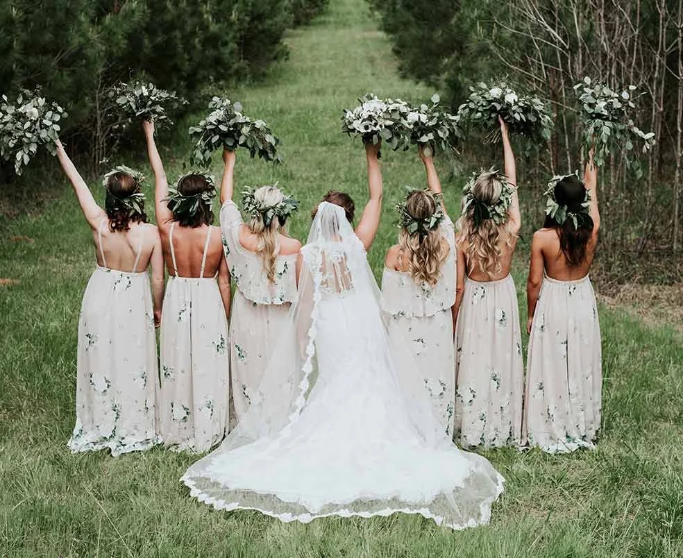 Braut und Brautjungfern mit floralen Kränzen und Blumensträußen bei einer Waldhochzeit im Raum St. Gallen – lockere Hochzeitsstimmung inmitten der Natur.