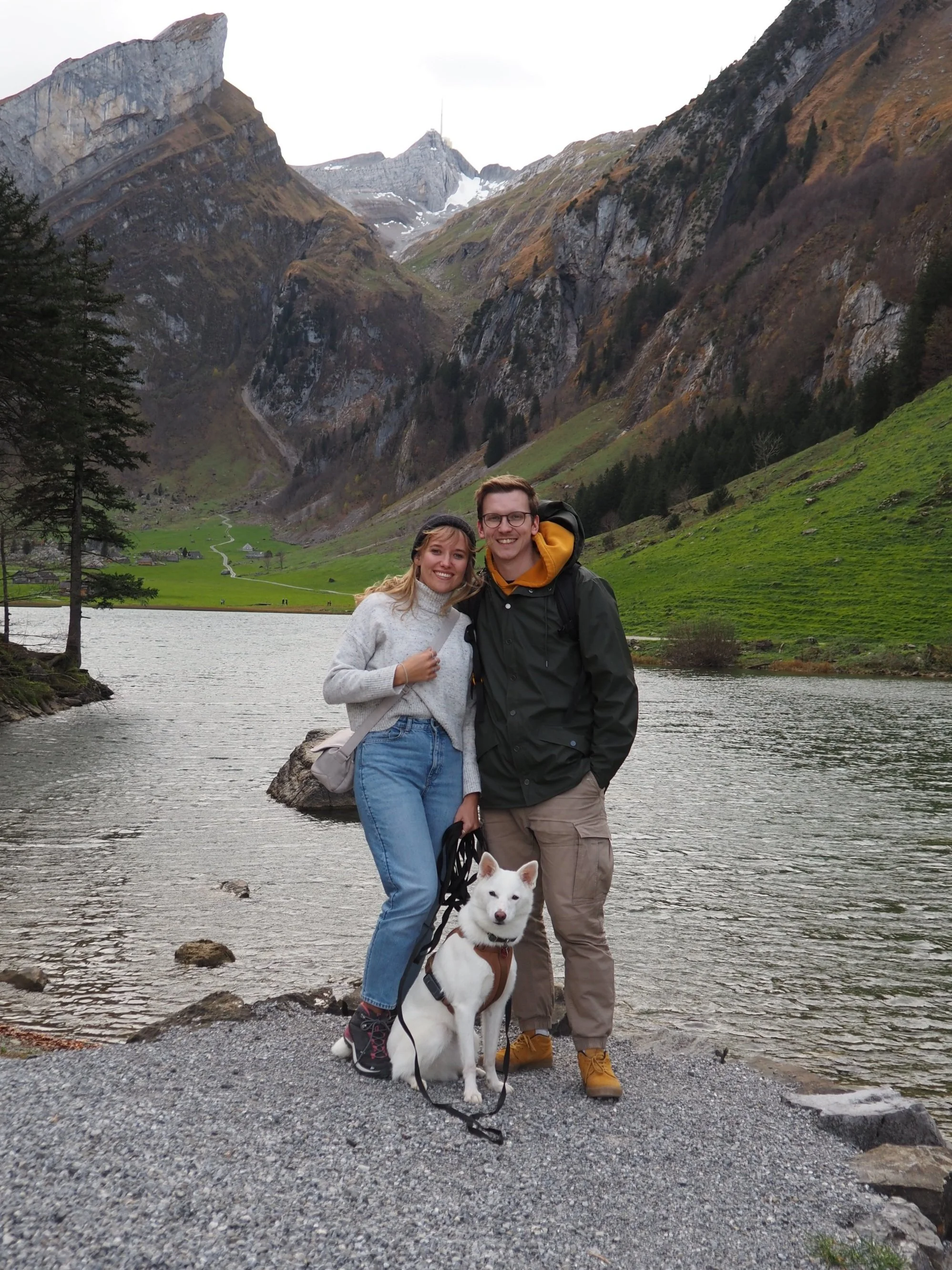 Hochzeitsplanerin Vanessa Schock mit ihrem Partner und Hündin Luna am Bergsee – lachend, naturverbunden und mit Blick auf die gemeinsame Zukunft in der Schweiz.