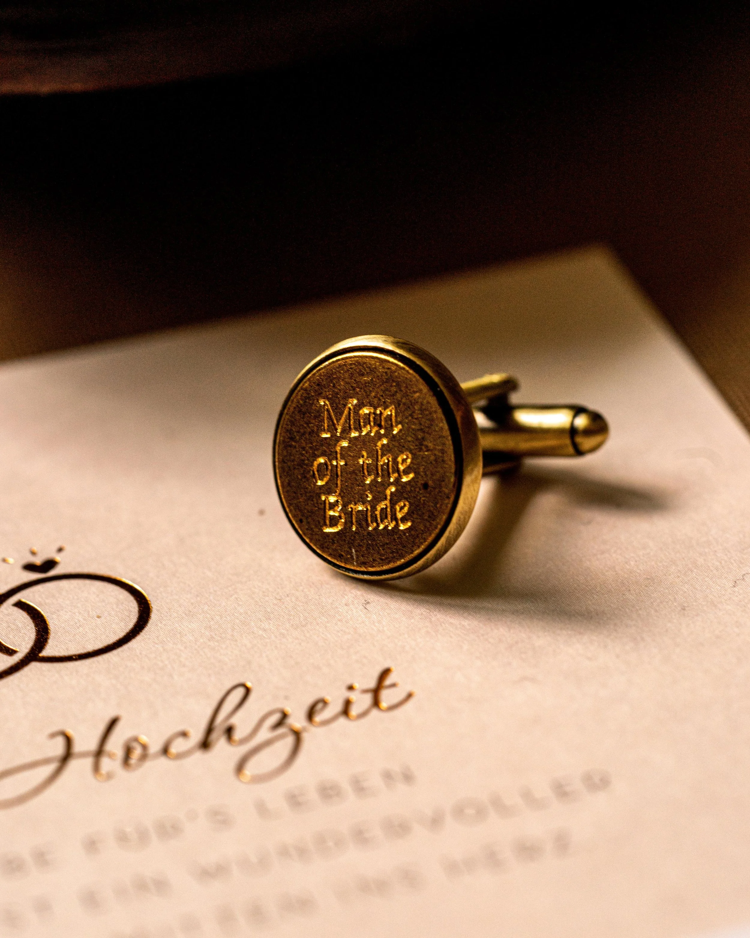 Goldene Manschettenknöpfe mit Gravur 'Man of the Bride' auf Hochzeitskarte.