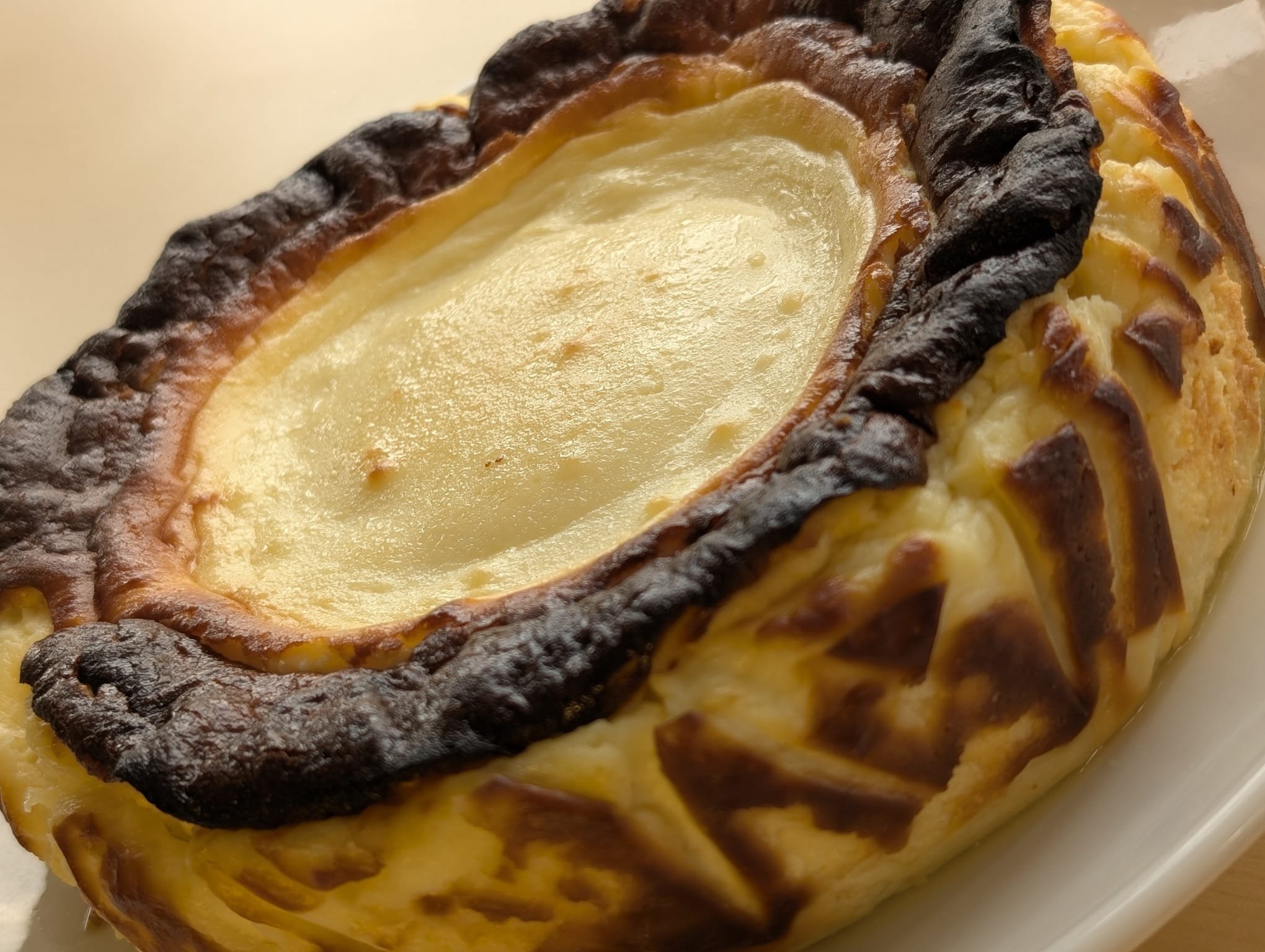 Close-up of a burnt basque cheesecake with a golden crust on a white plate.