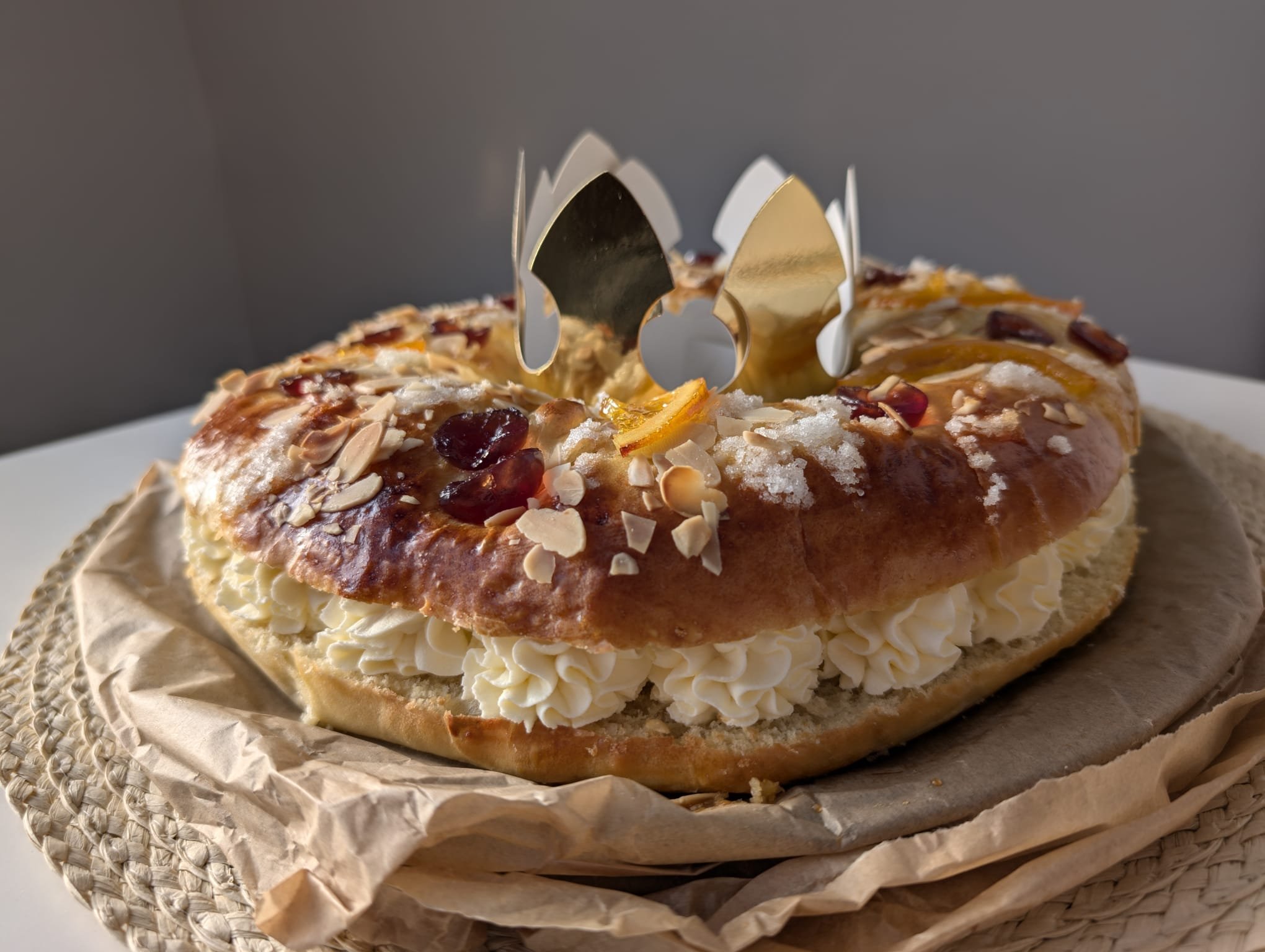 Cream-filled Roscon de Reyes with almonds and candied fruit topping and gold paper crown