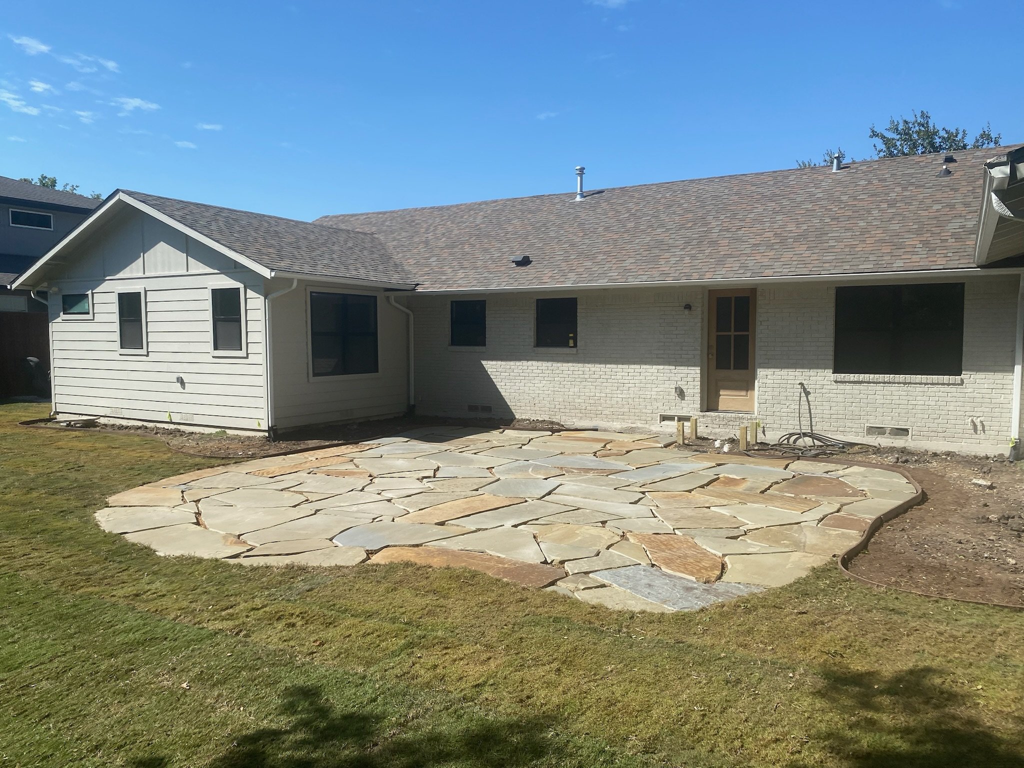 After: flagstone patio with irrigation, grading, and garden bed steel edging in Dallas TX