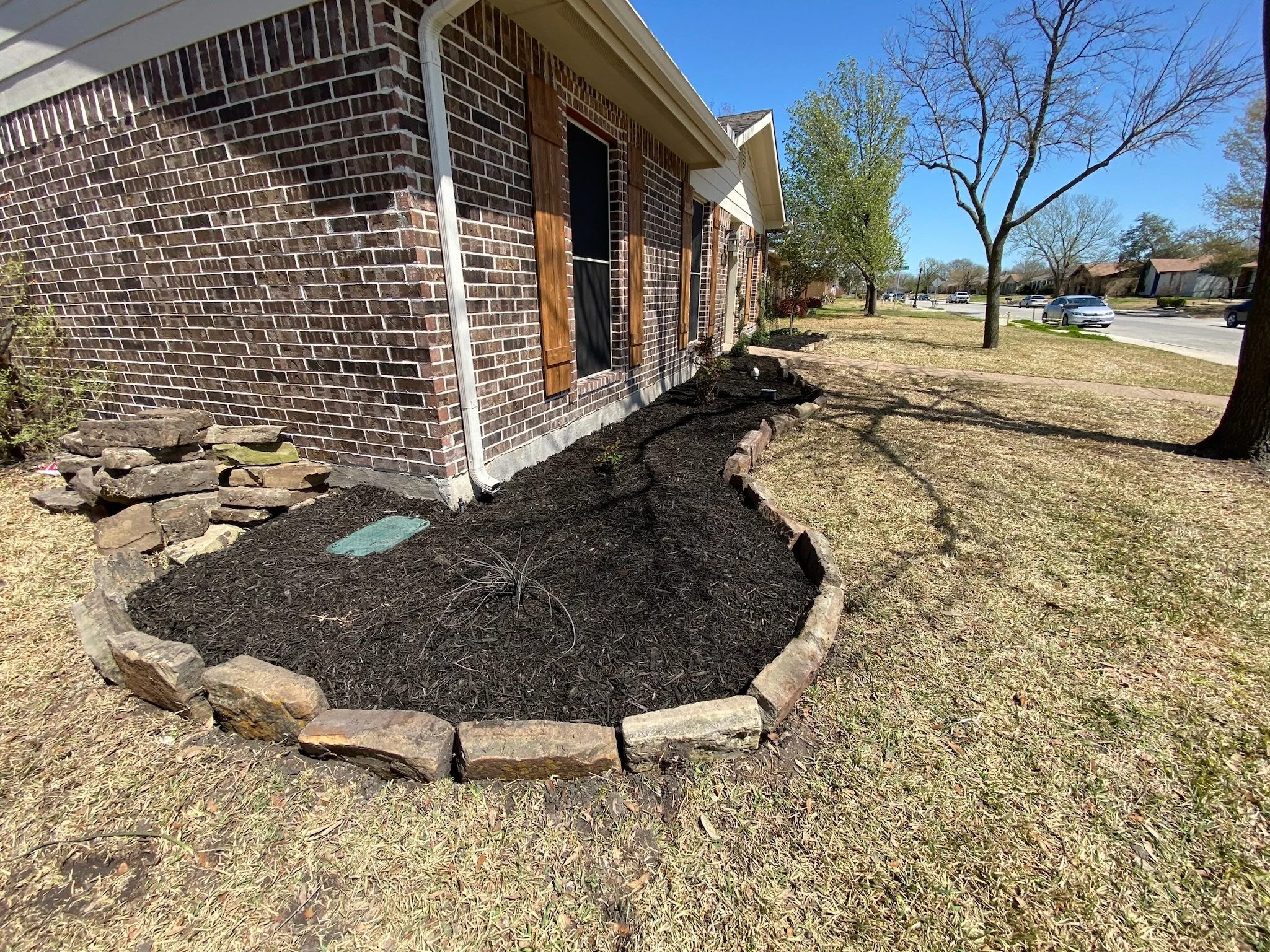 After photo showing newly shaped garden bed edges and fresh mulch in Garland, TX.