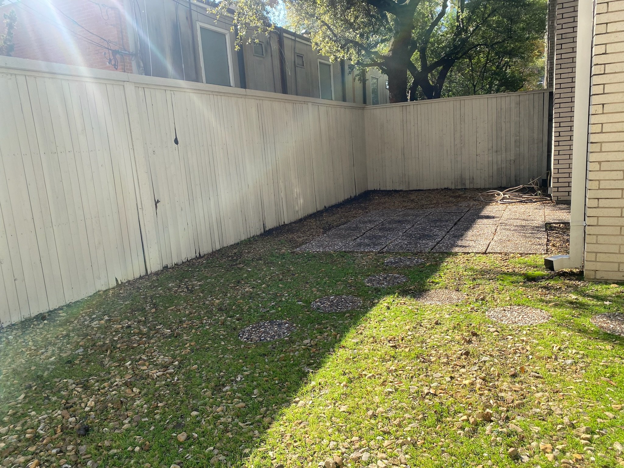 Before photo showing heavy weed growth across a gravel patio in Dallas, TX.
