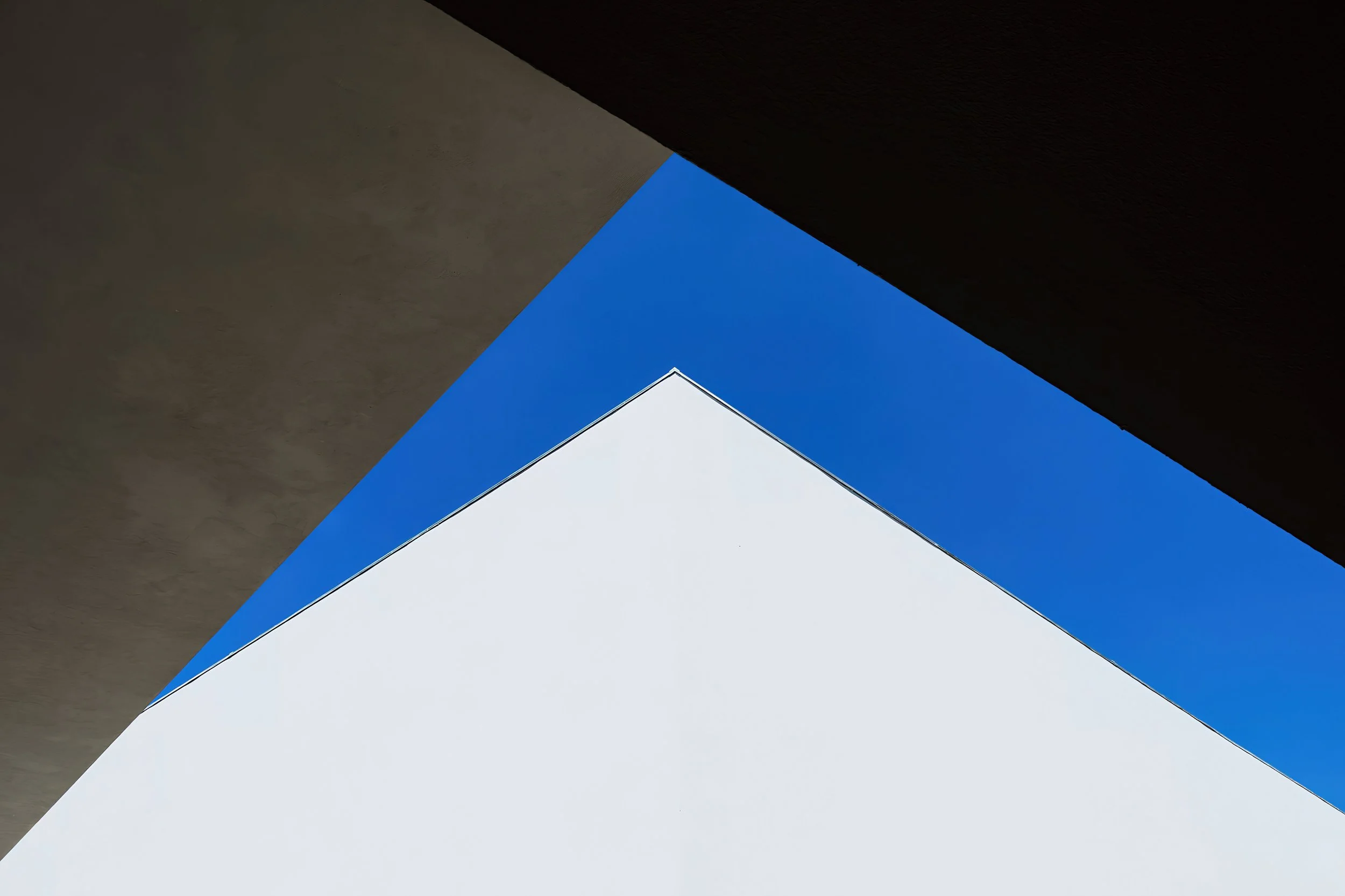 Low-angle view of modern building with white, black, and blue geometric shapes and clear sky in the background.