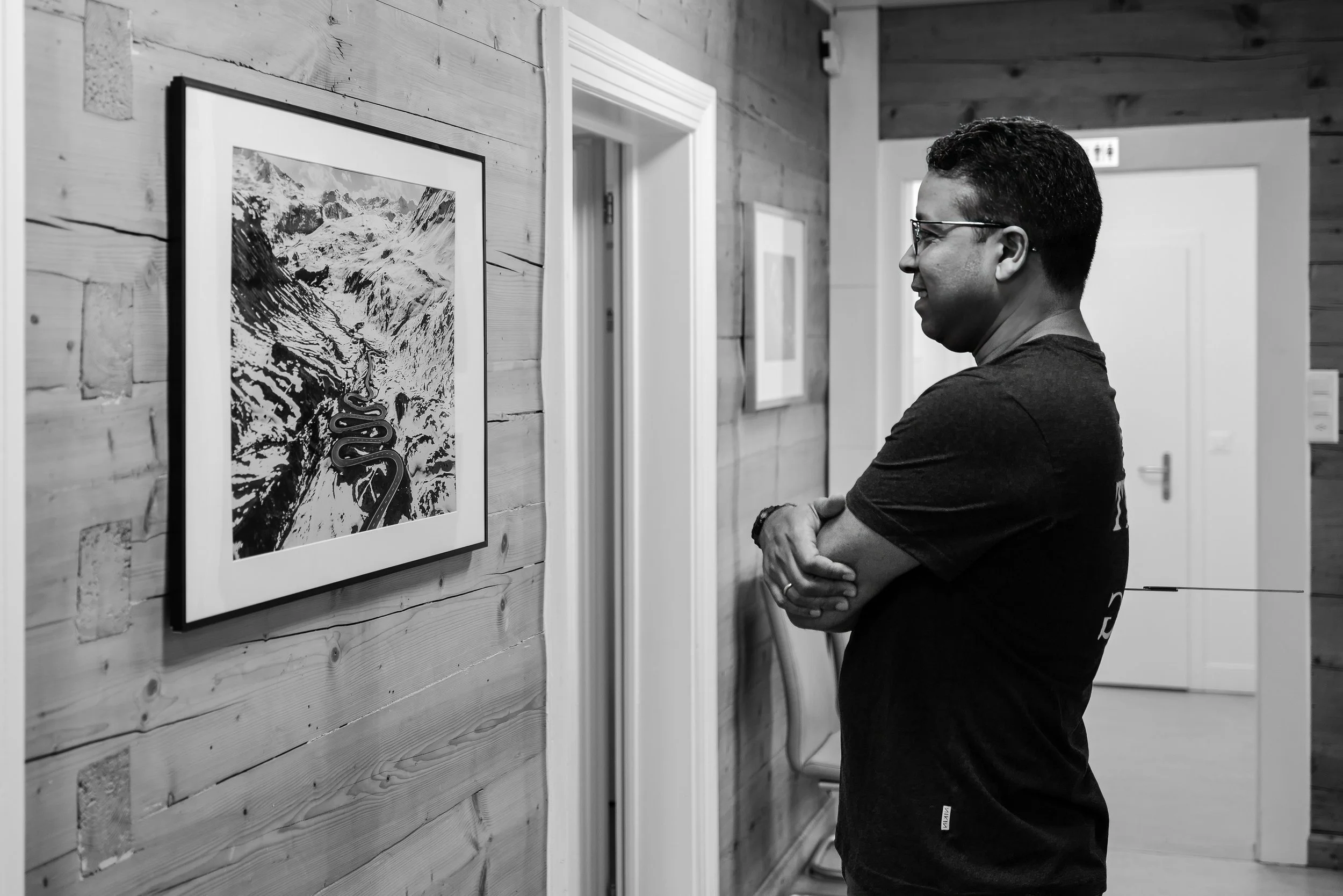 A man observing artwork in an art gallery with wood-paneled walls.