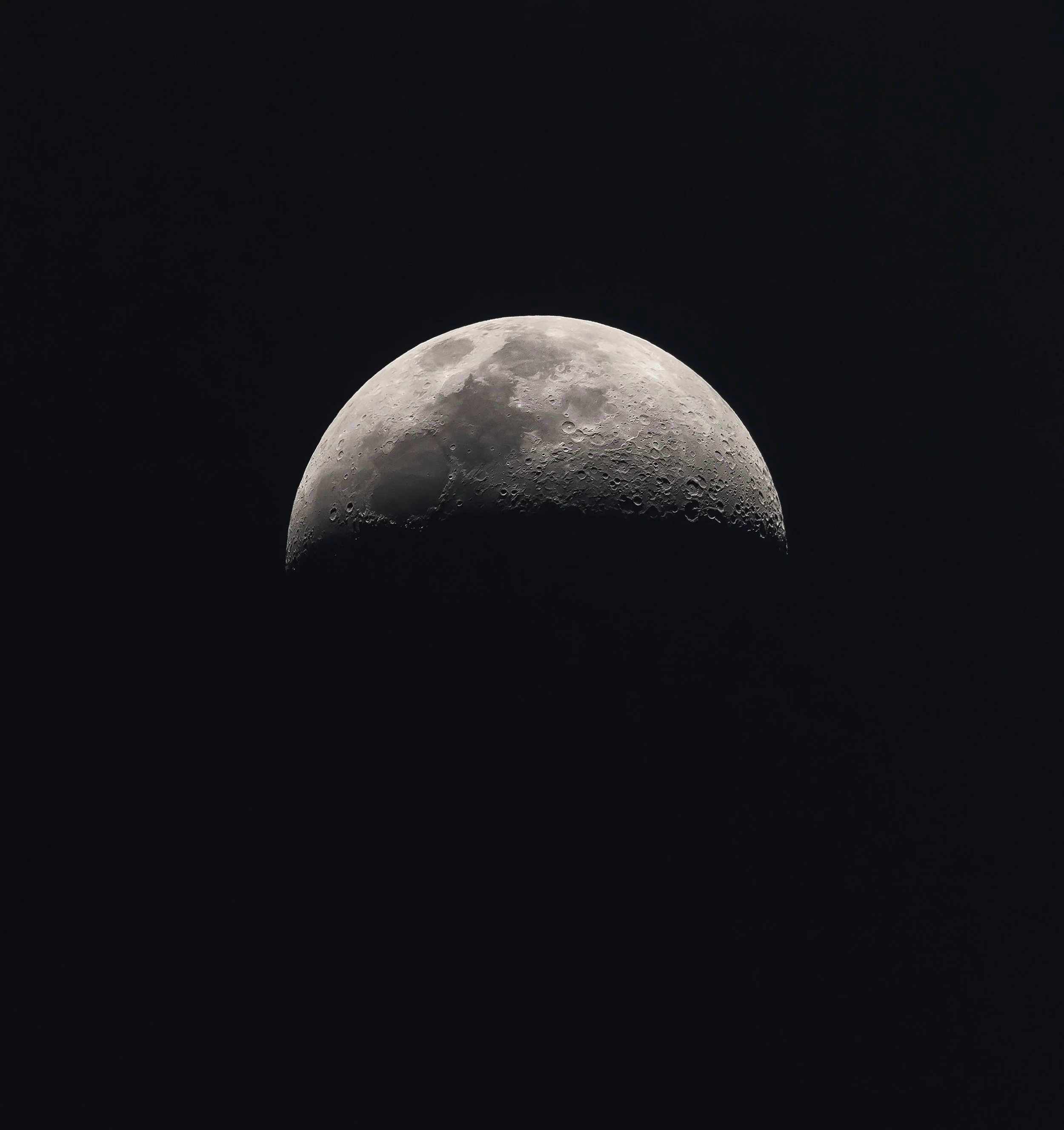 Close-up photograph of the moon showing craters and surface details with a dark space background.