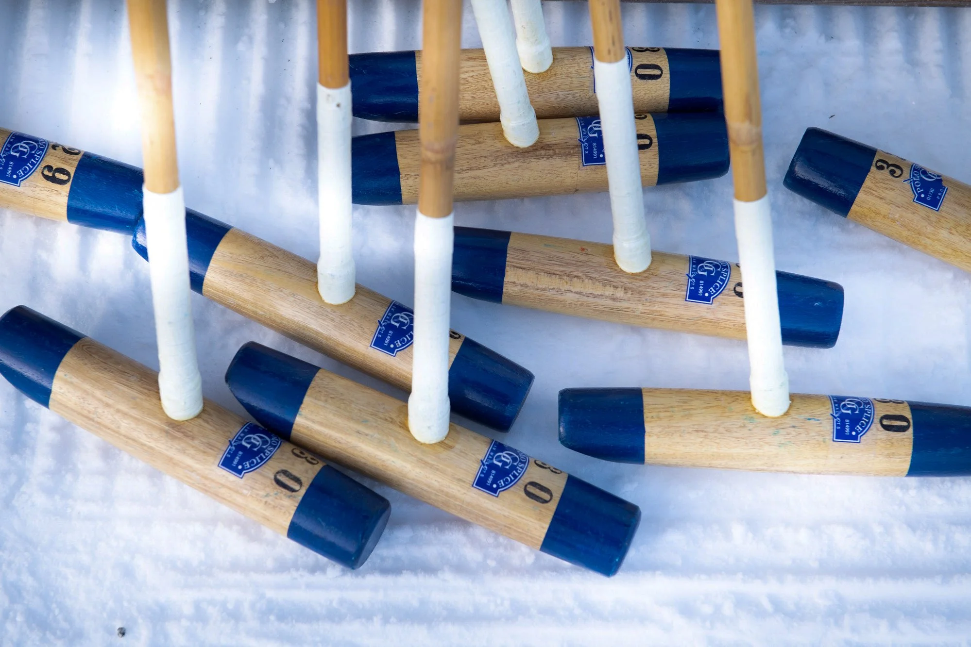 Multiple wooden and blue snowshoe bindings placed on snow.