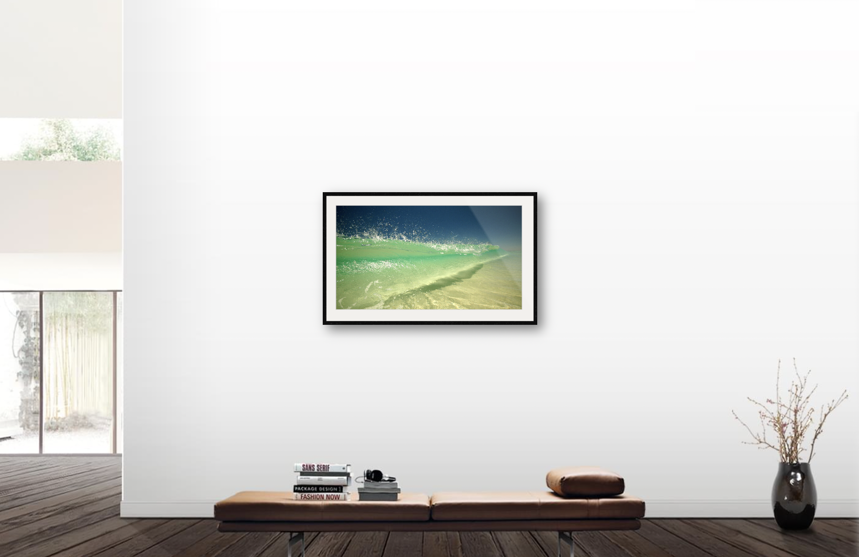 Modern living room with a framed ocean wave photo on the white wall, a low wooden bench with books and headphones, a rolled-up cushion, and a tall vase with dried branches.