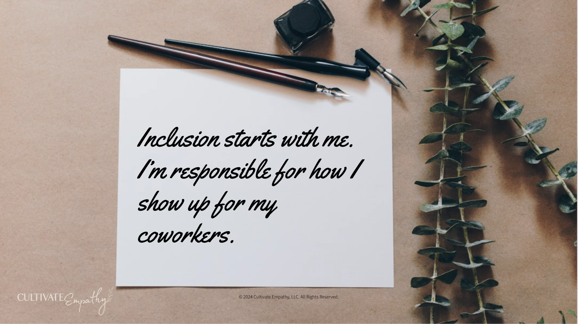 A handwritten quote on a white piece of paper that reads, 'Inclusion starts with me. I'm responsible for how I show up for my coworkers.' The paper is laid on a brown surface, with two black fountain pens, a small ink bottle, and a green leafy plant 