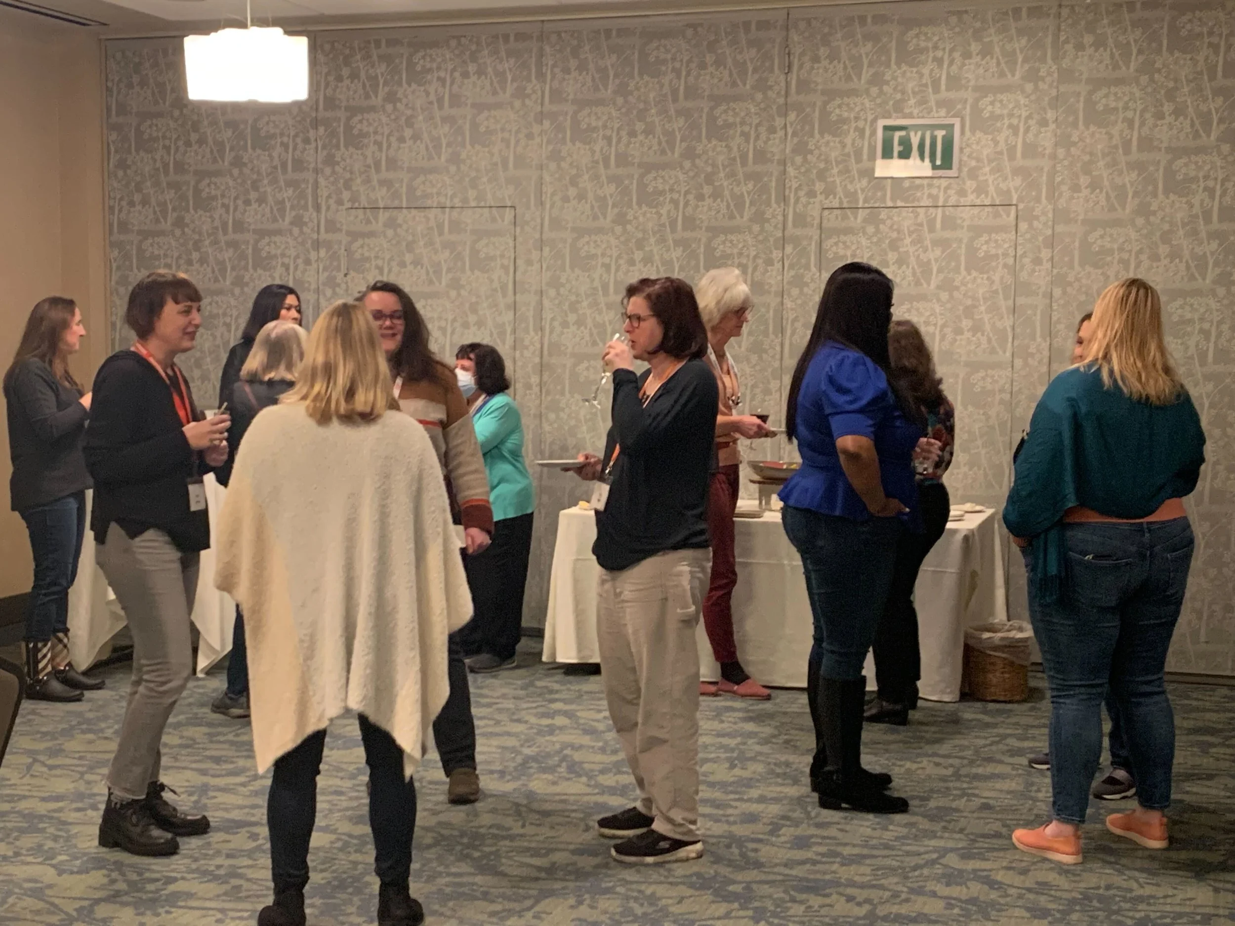 Group of women engaging in conversation at a professional networking event in a conference room.