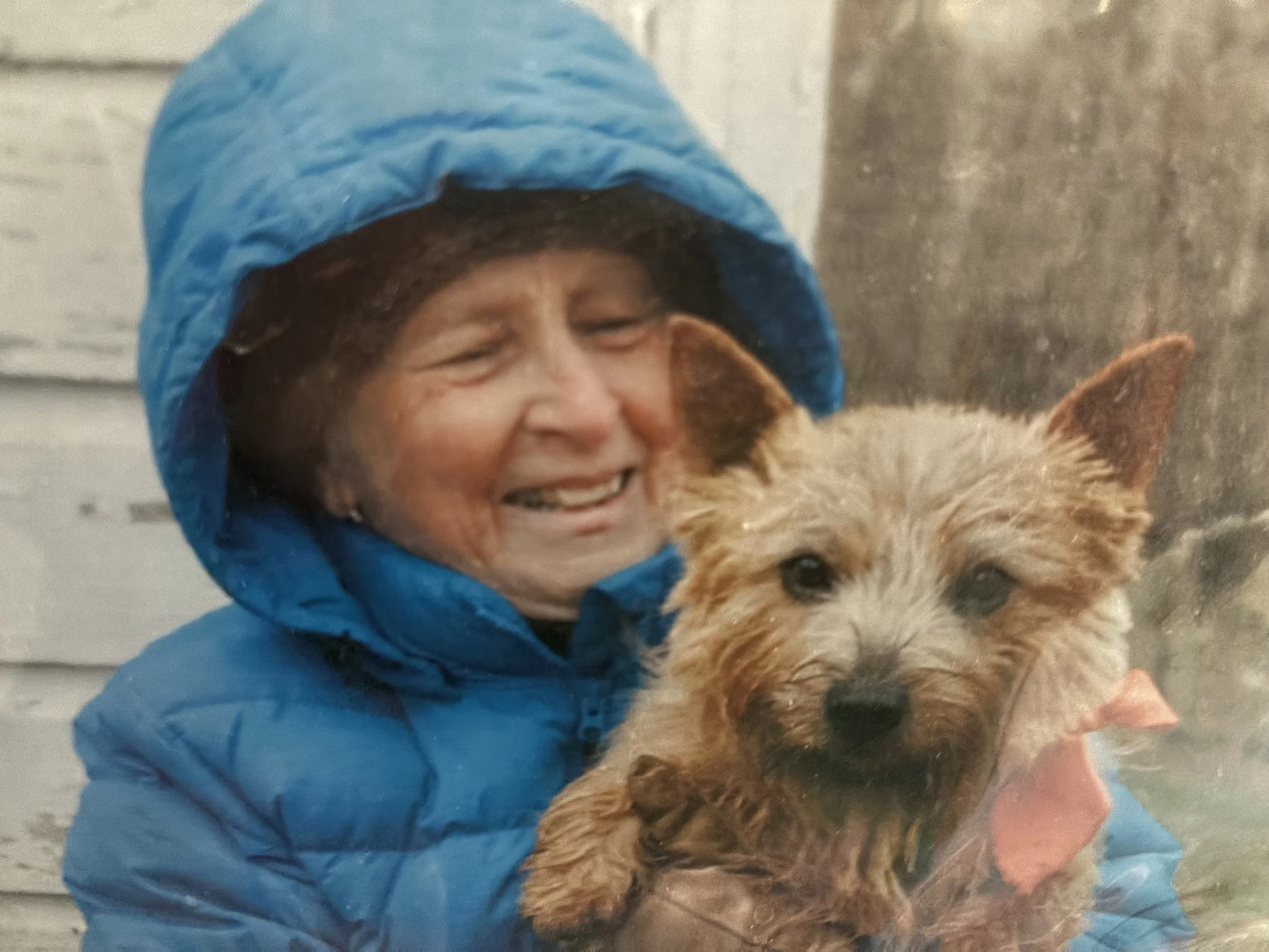 A photo of a woman smiling holding a small dog.
