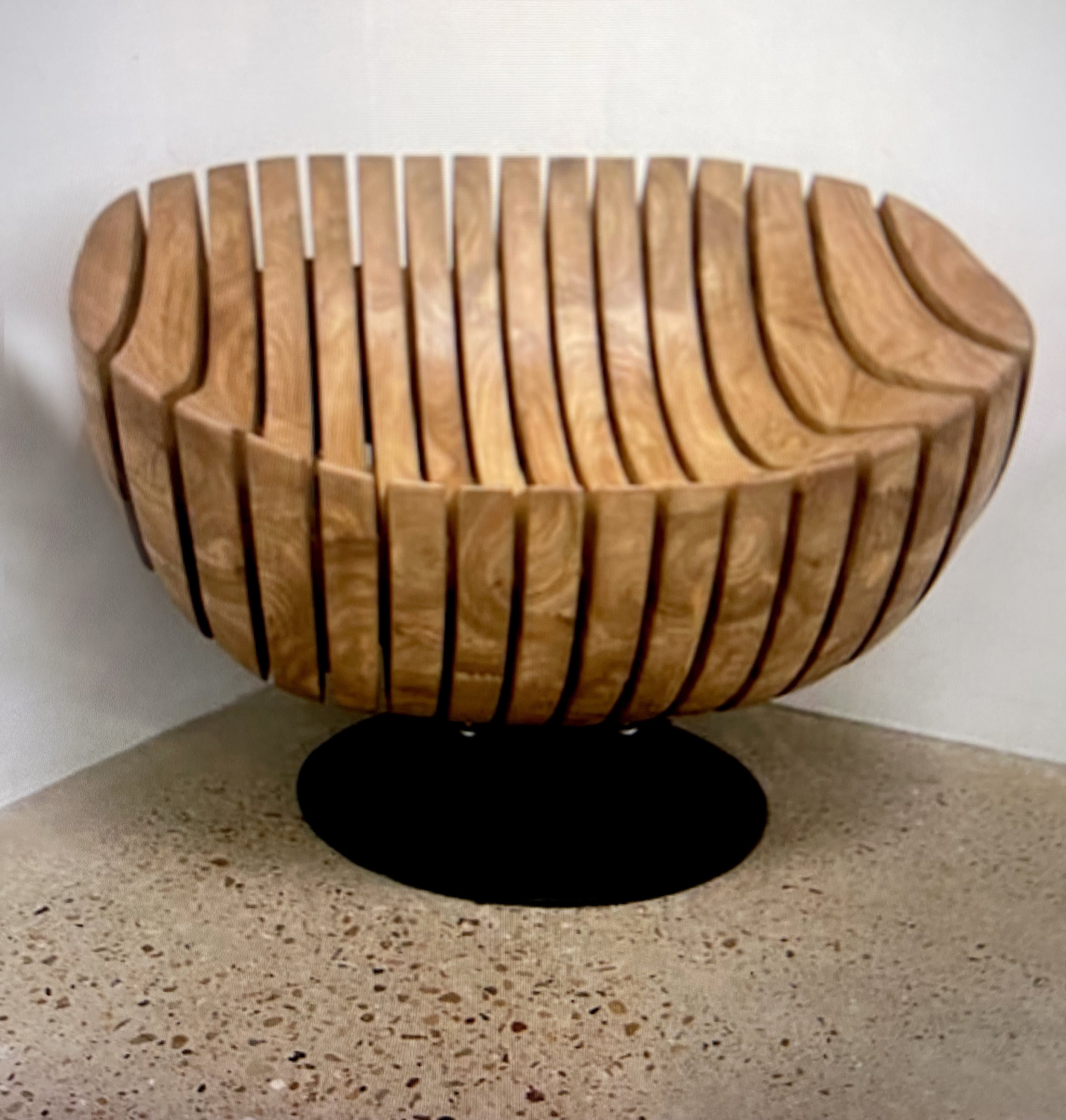 A modern wooden chair with a striped design and a black base,.