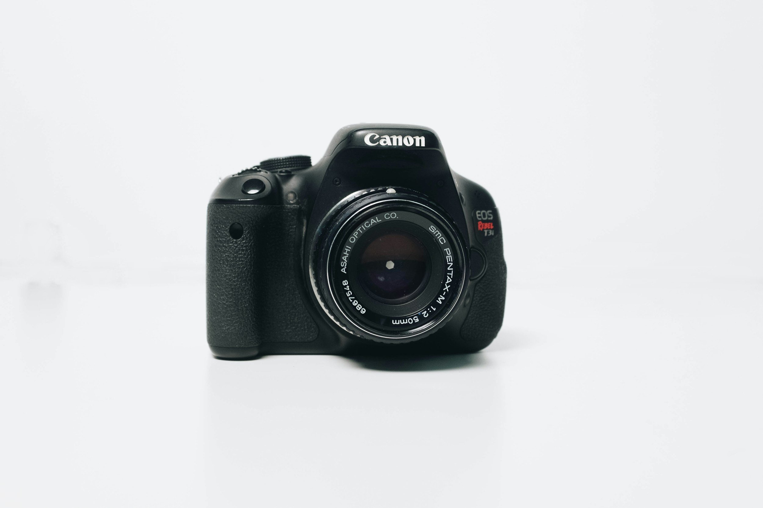 A black Canon EOS Rebel T3i camera with a zoom lens, positioned against a plain white background.