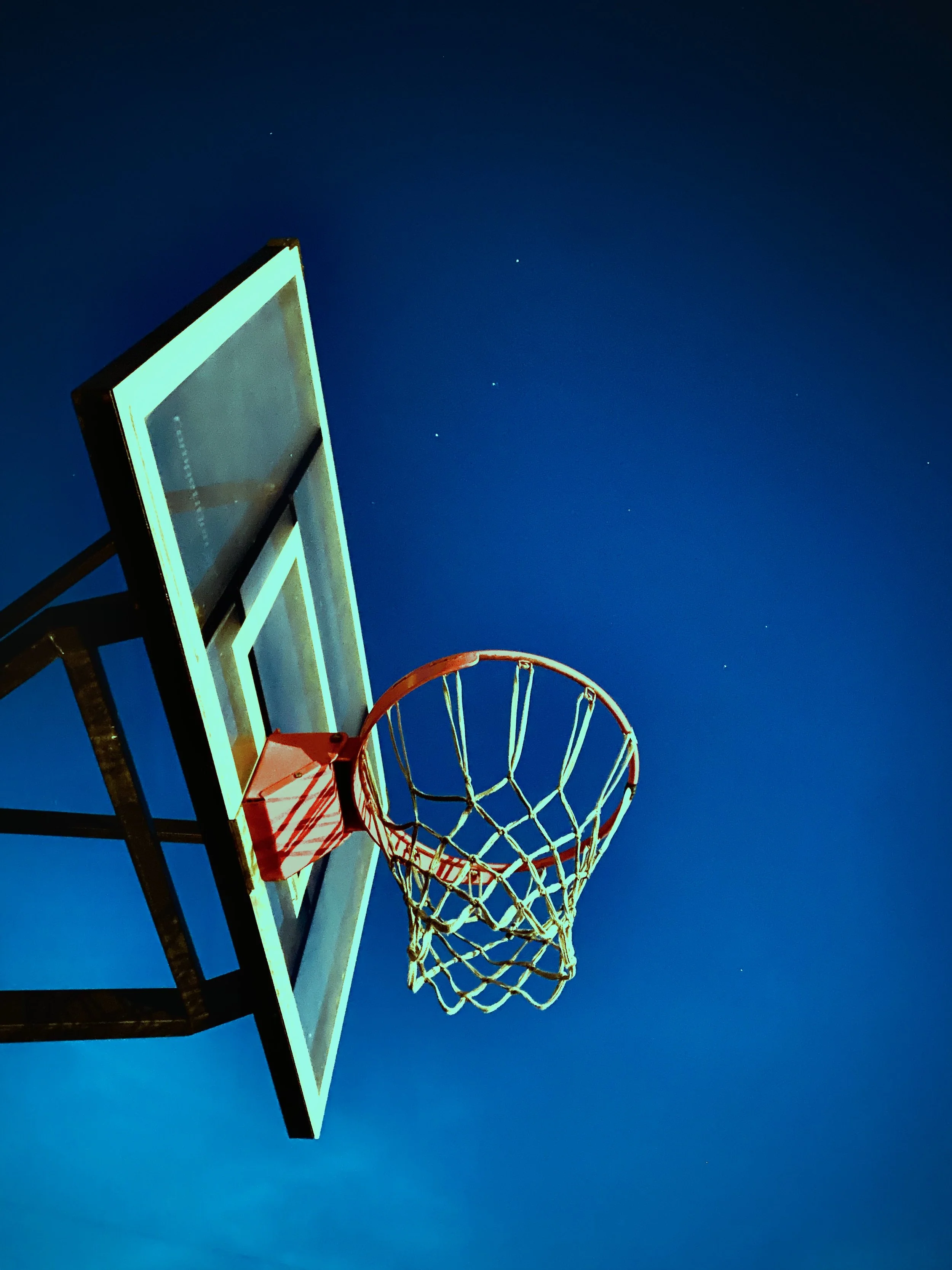 Basketball hoop with net under a night sky with visible stars.