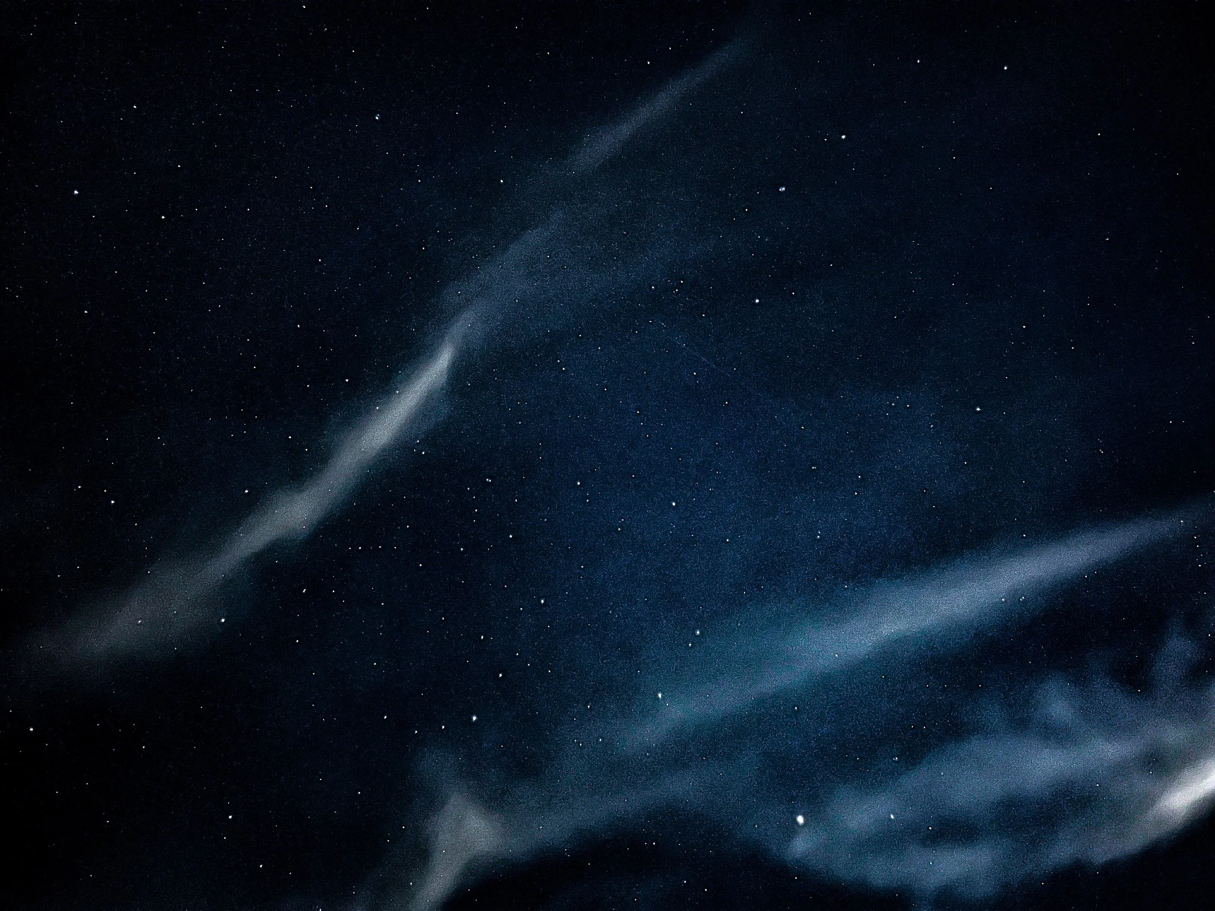 Night sky filled with stars and wispy clouds.