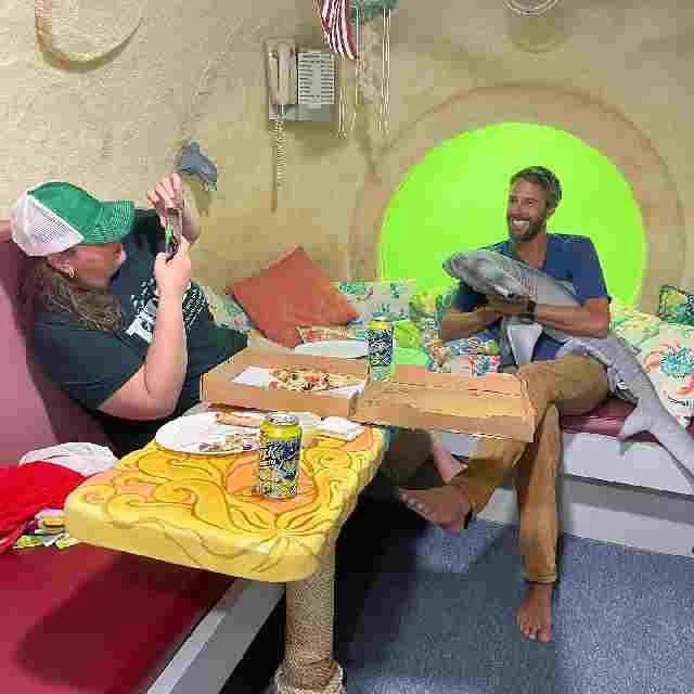 The galley extends the width of the habitat, with a counter, sink, small fridge, and microwave at one end and this table and sitting area at the other end.