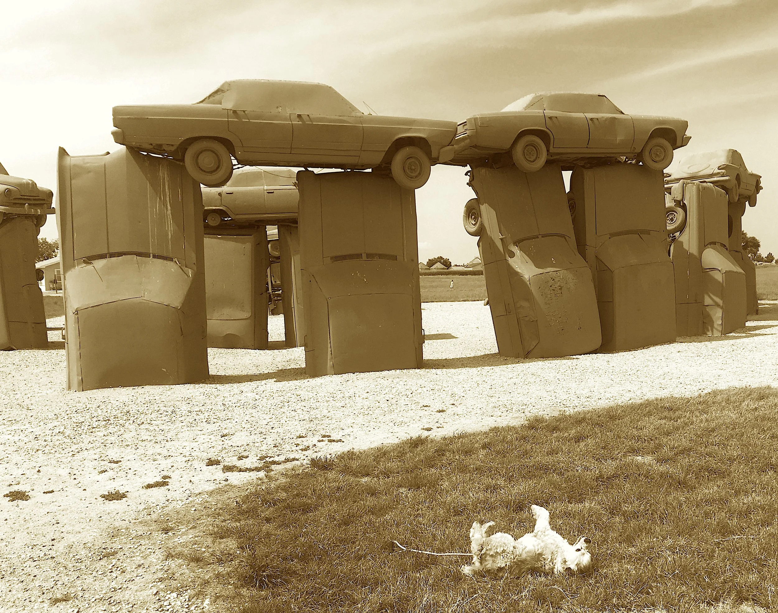 Where sedans rise like stones on the plain,
A tribute to Dad in metal and chain.
Midwestern Stonehenge with hubcap reign.