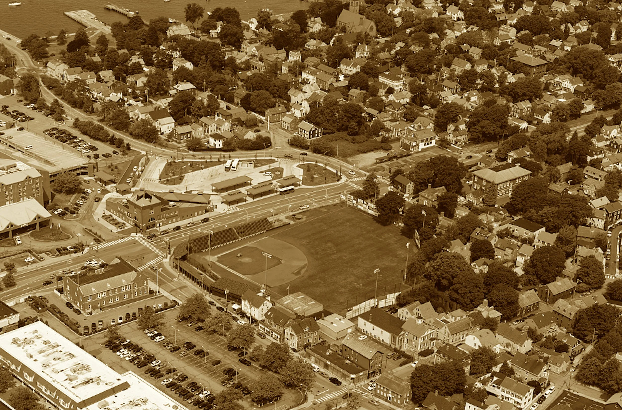 Where outfield trees might steal a run,
And curving bleachers face the sun—
Newport's ballgame's never done.
A diamond tucked in city bends,
Where railmen played and joy extends—
And summer league tradition lends.