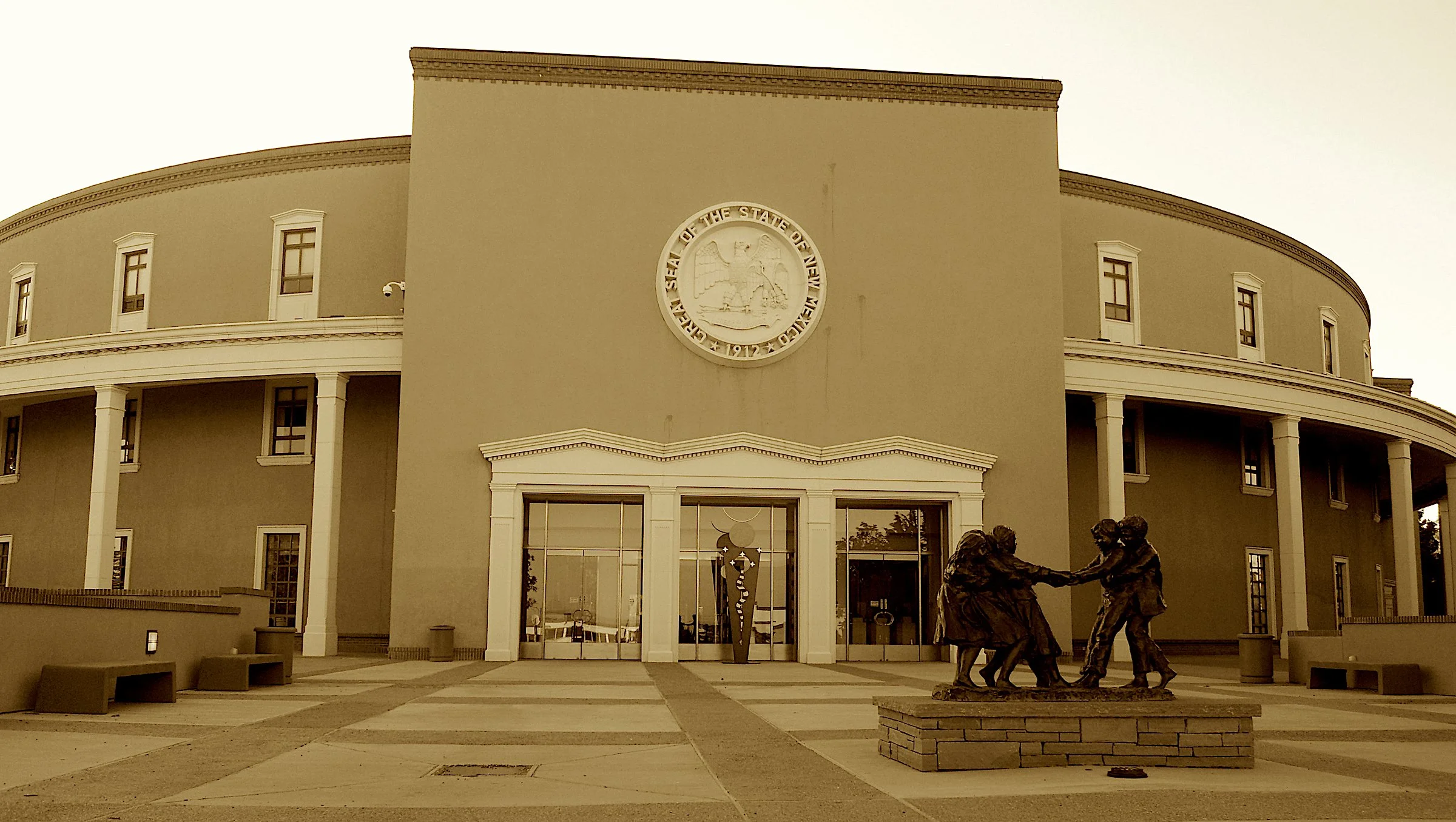 It’s round like the sun on the state’s Zia crest,
With baskets and skylights and art on request.
Four styles united in circular pride,
Where statecraft and sculpture sit side by side.
The nation’s one Roundhouse, with flair and with roots—
Where legi