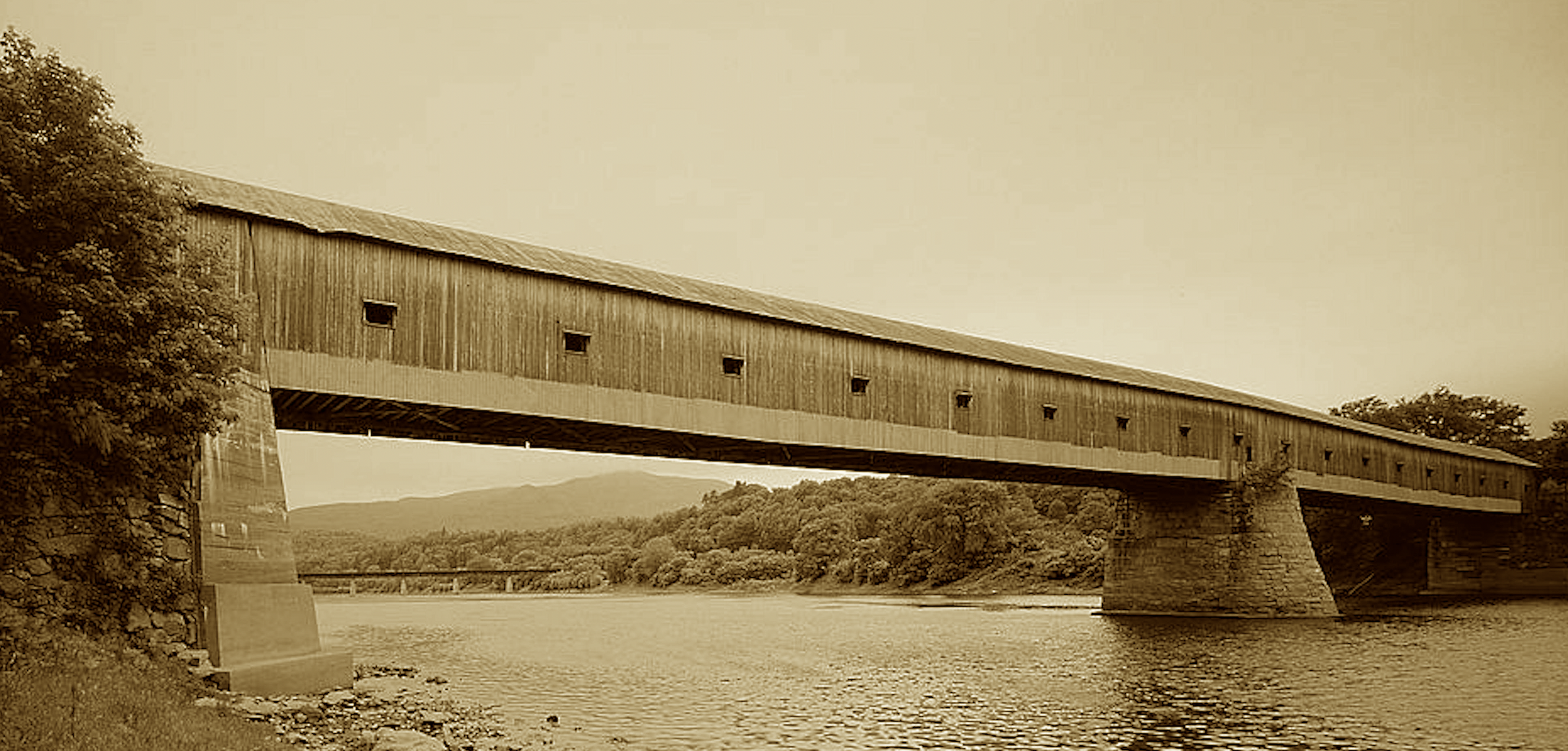 At 460 feet it spans with grace,
A lattice truss in timeless place.
From toll to free, it’s carried through—
New England’s charm in timber true.