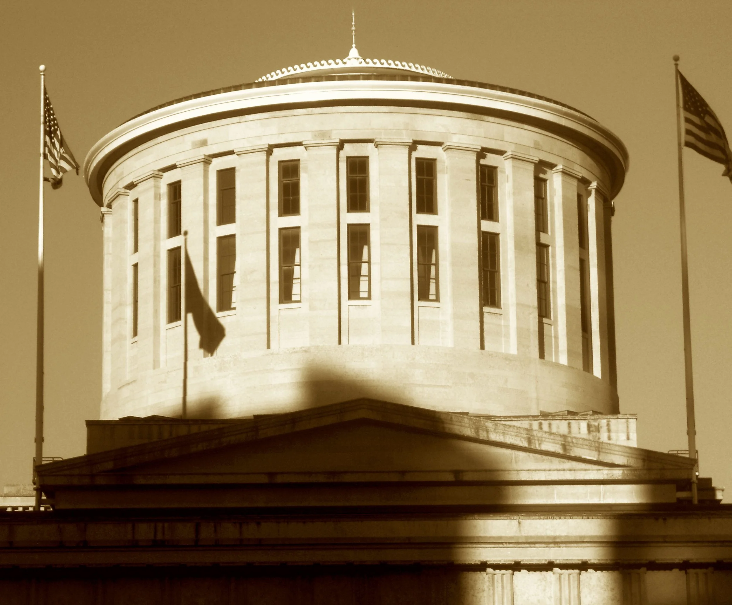 With limestone pulled from the Scioto’s near flank,
And columns that mirror an old Grecian bank,
This beacon of law rose in measured command,
Its cupola glowing above the flat land.
Where Doric meets destiny on every floor,
Ohio’s own Athens stands p