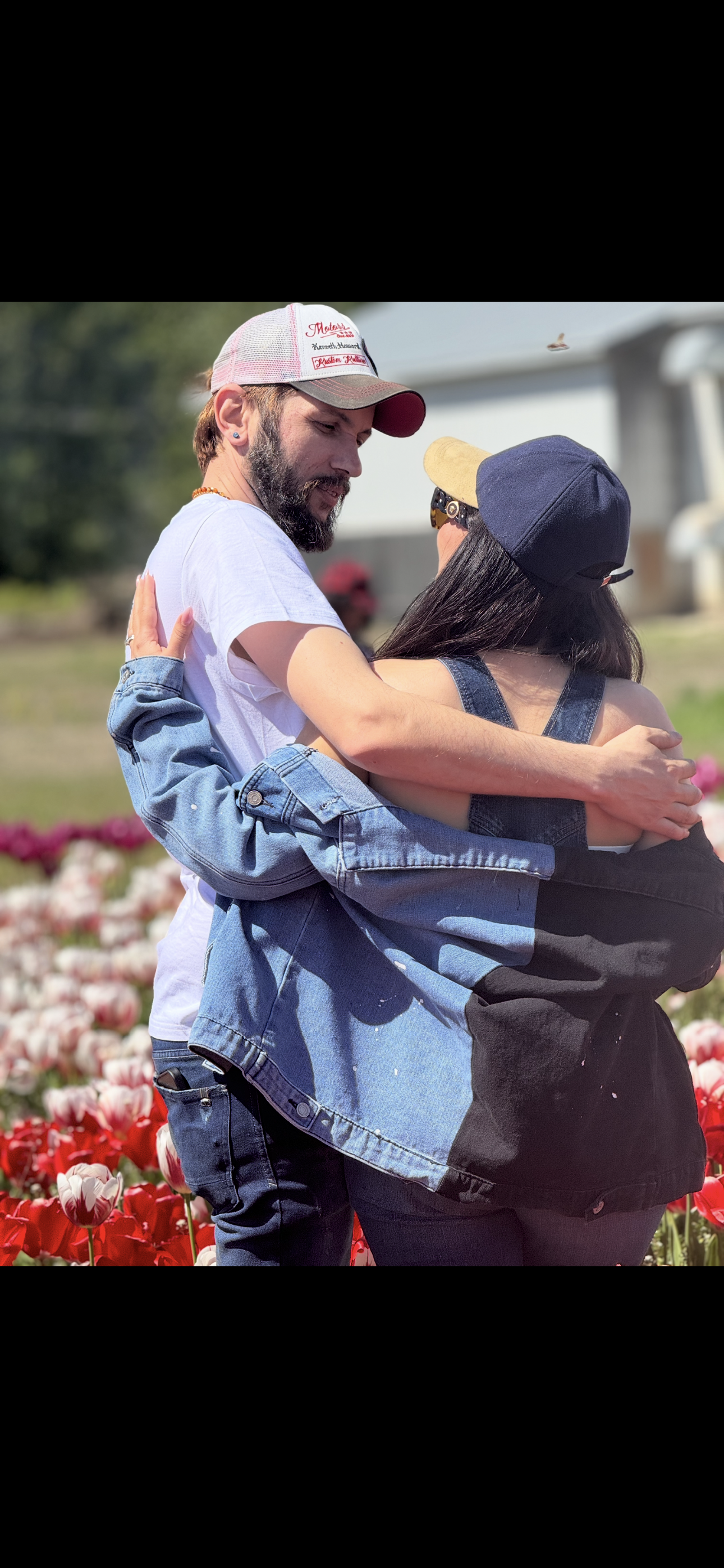 A man and woman hugging in a flower field.
