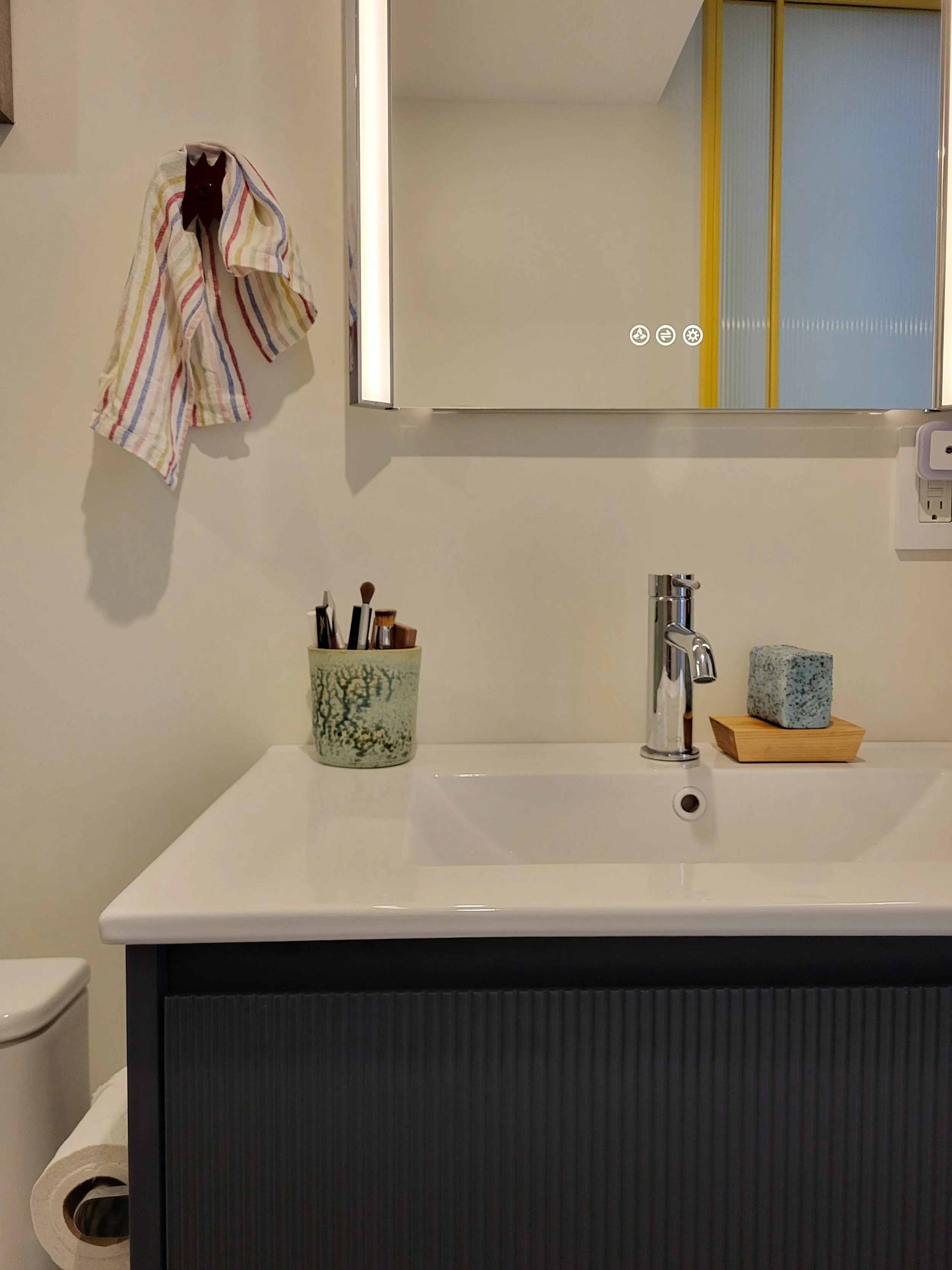 An Upton Home hook in action near the LED dimmable mirror. The ribbed vanity and tower mimic the ribbed glass door. 