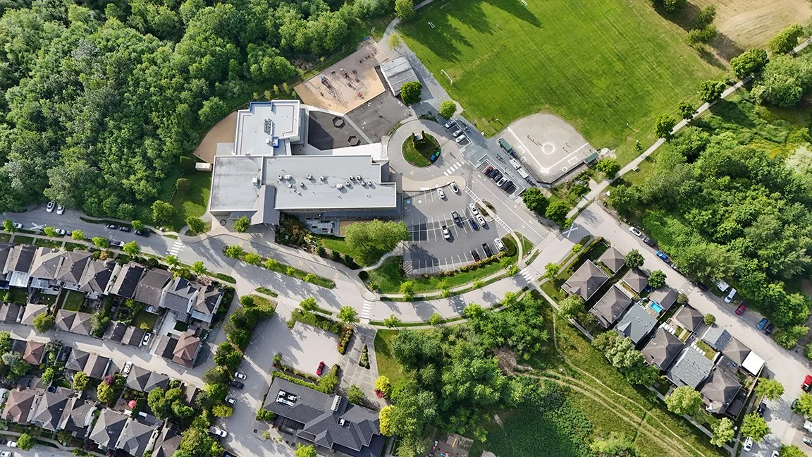 Aerial view of a residential neighborhood with a school, parking lot, and green spaces.