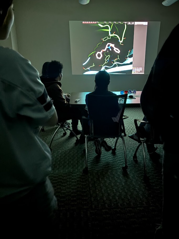 Group of people watching a presentation on a large screen in a dark room.