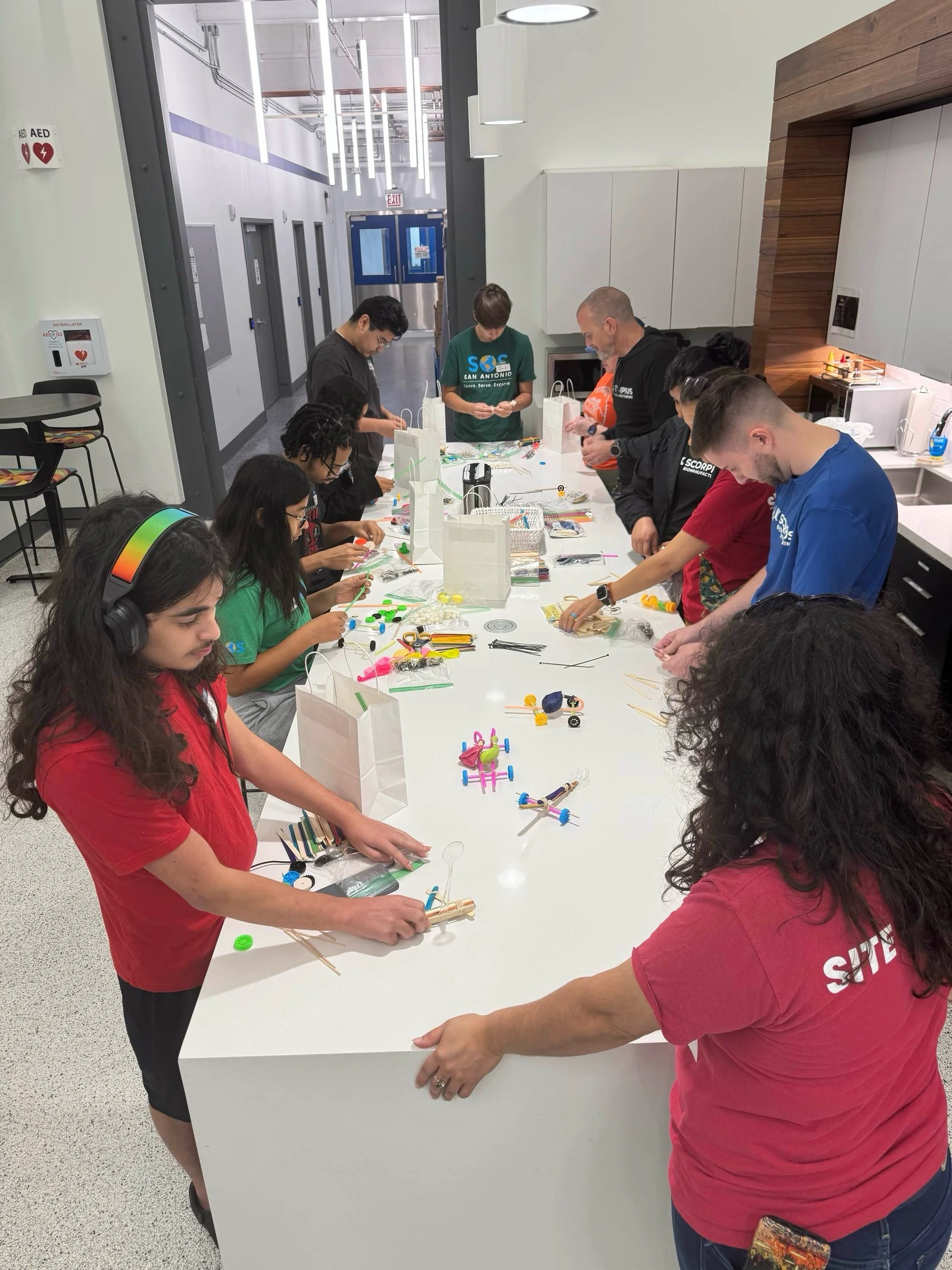 Students working on arts and crafts at a long table in a bright, modern room.