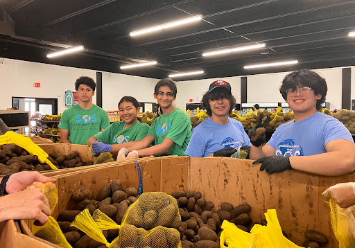 Group of five young volunteers sorting food in a community kitchen..