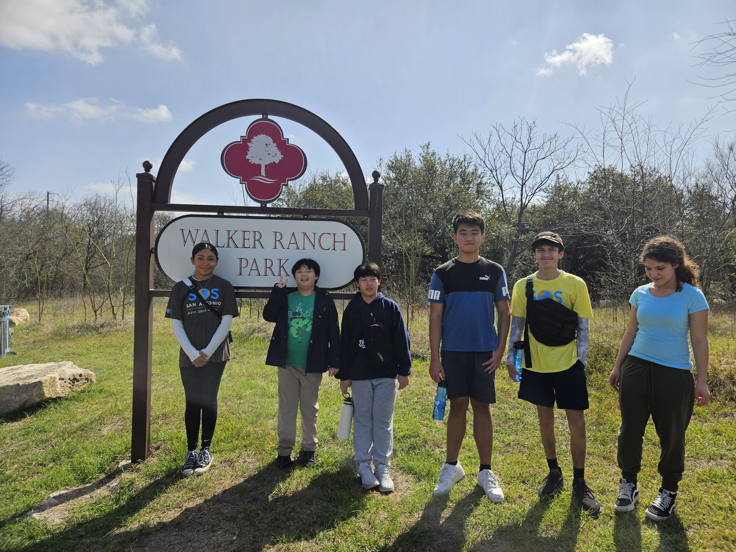 Group of six teenagers standing in front of a sign for Walker Ranch Park, outdoors on a sunny day.