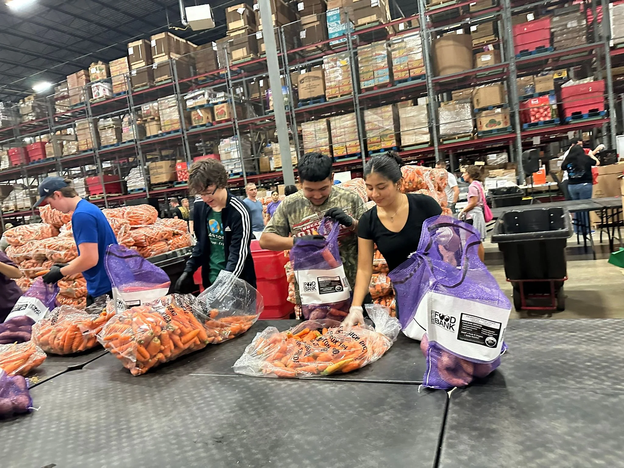 Group of volunteers packing bags with carrots and sweet potatoes at San Antonio Food Bank.
