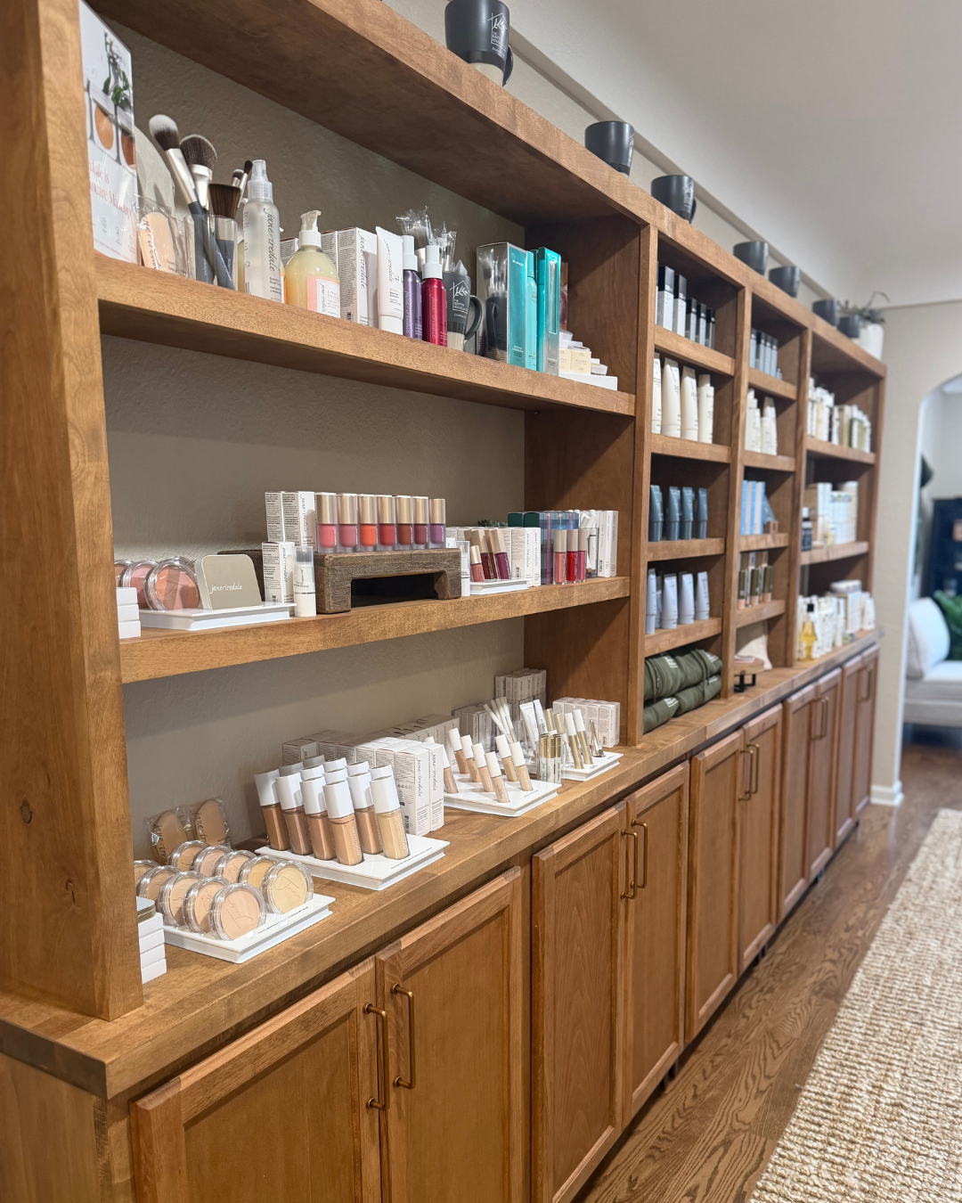 Display of various scented candles and home decor items arranged on wooden and white shelves in a store.
