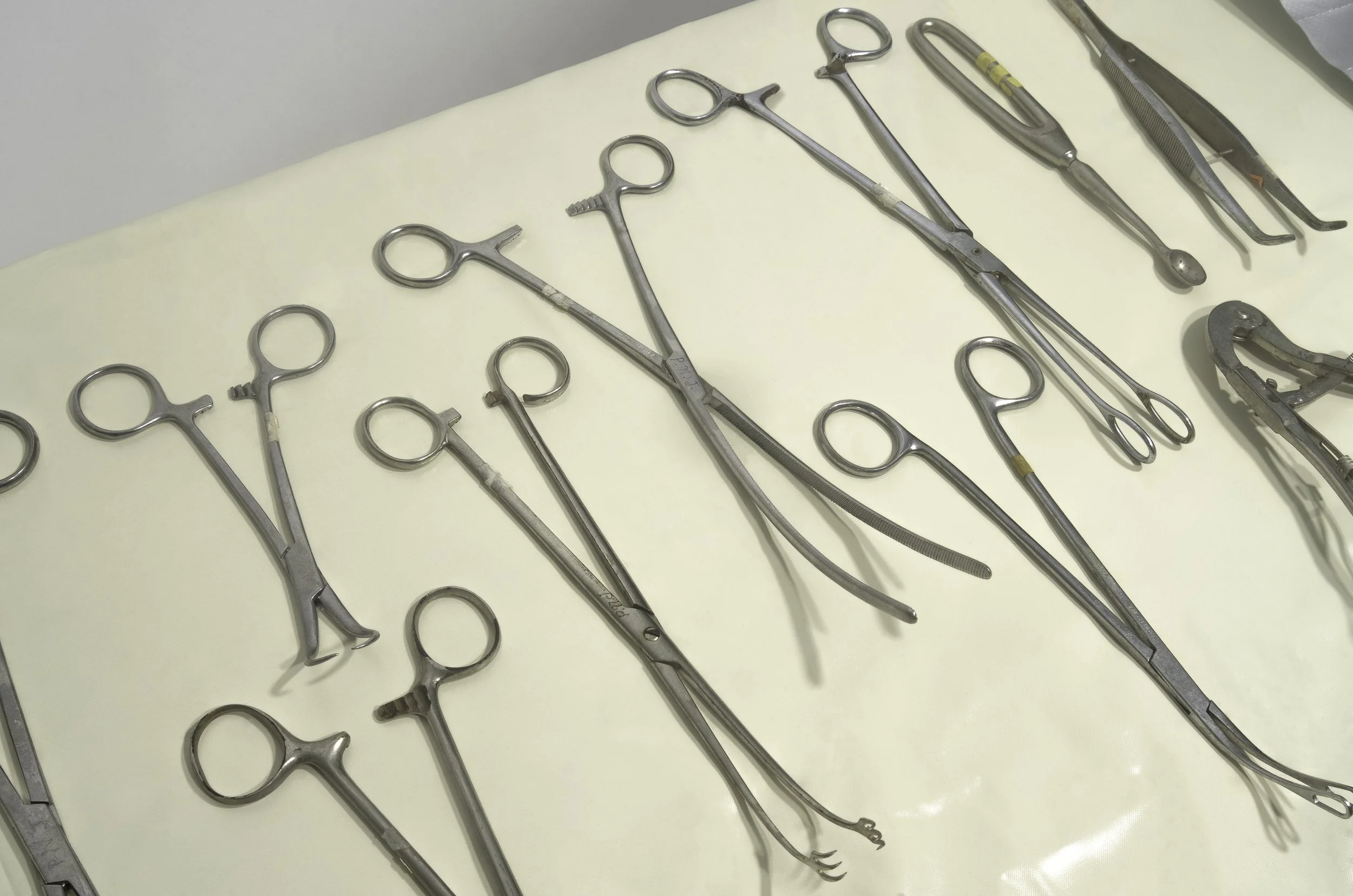 Collection of surgical tools, including forceps and clamps, laid out on a medical tray.