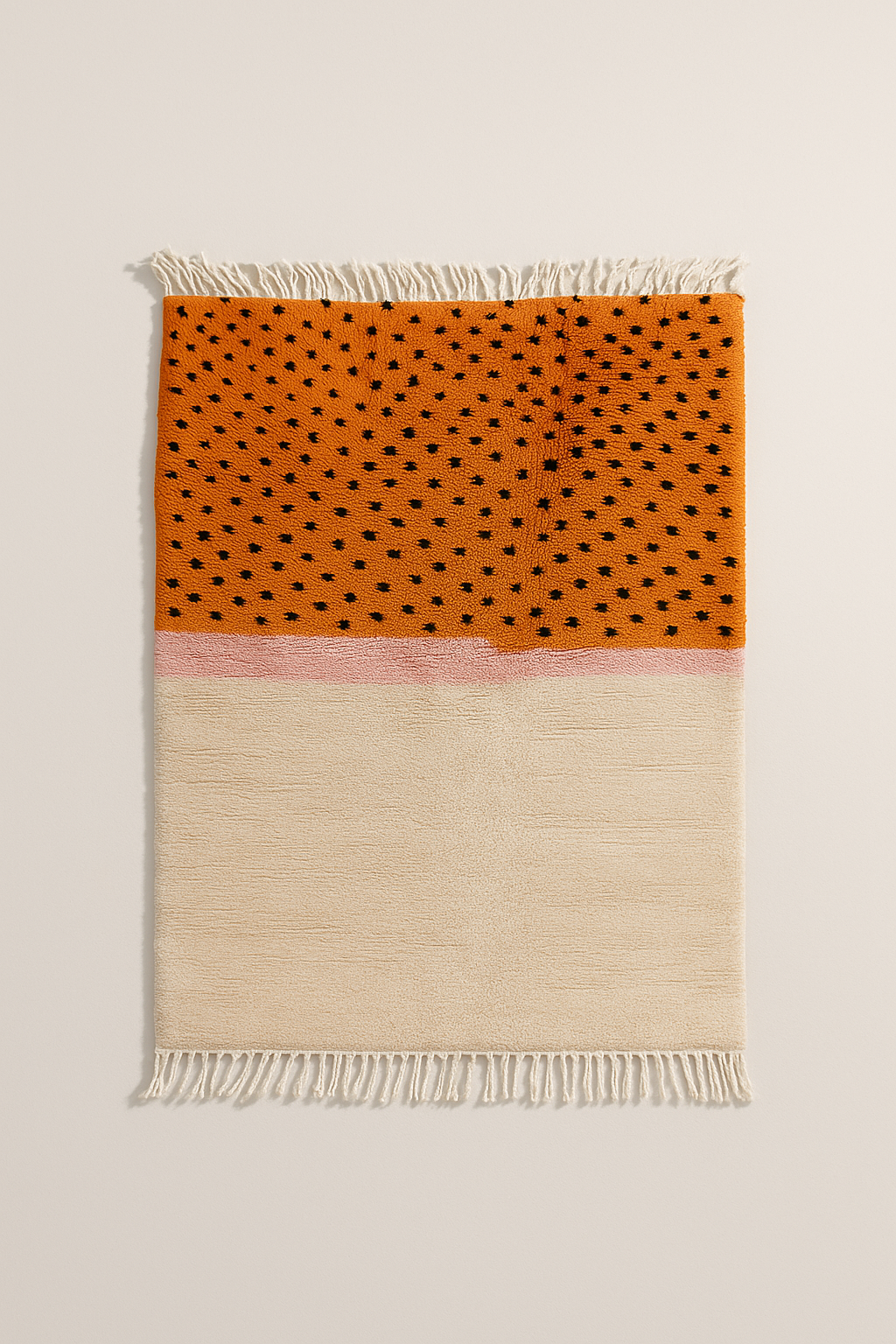 Tapis coloré avec une moitié orange à pois noirs et une moitié crème avec des franges