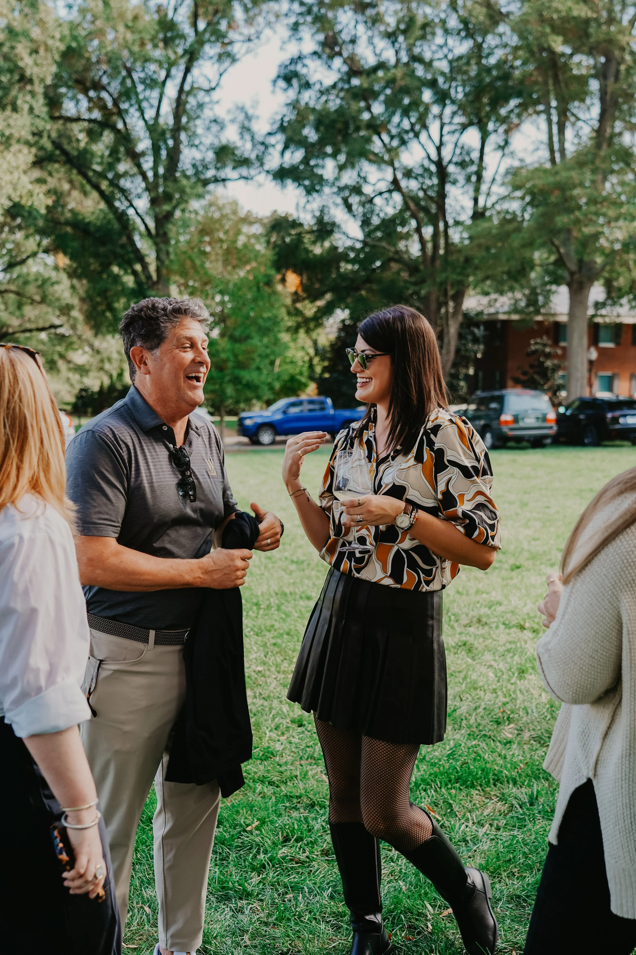Group of people talking and smiling outside in a park during daytime.