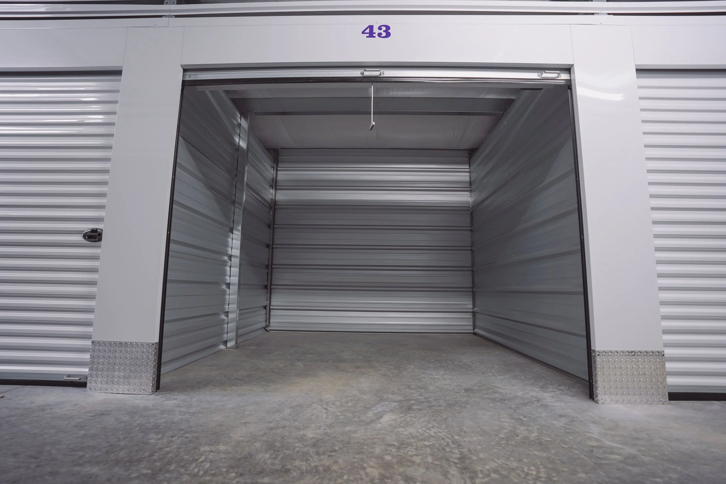 An open storage unit with metal walls and a concrete floor, labeled number 43.