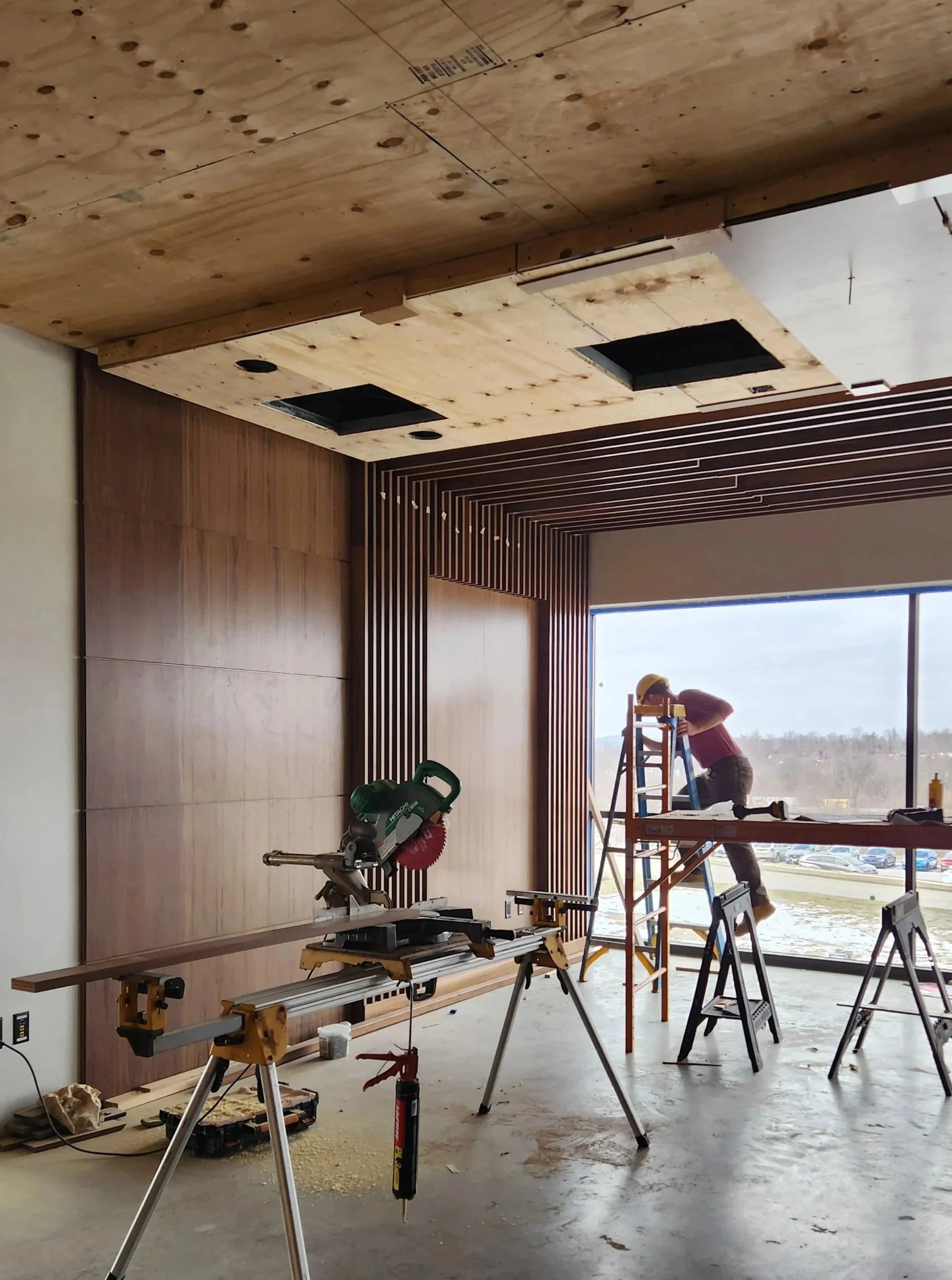 Interior under fabrication of Ace Endico with us installing wooden slats on the ceiling.