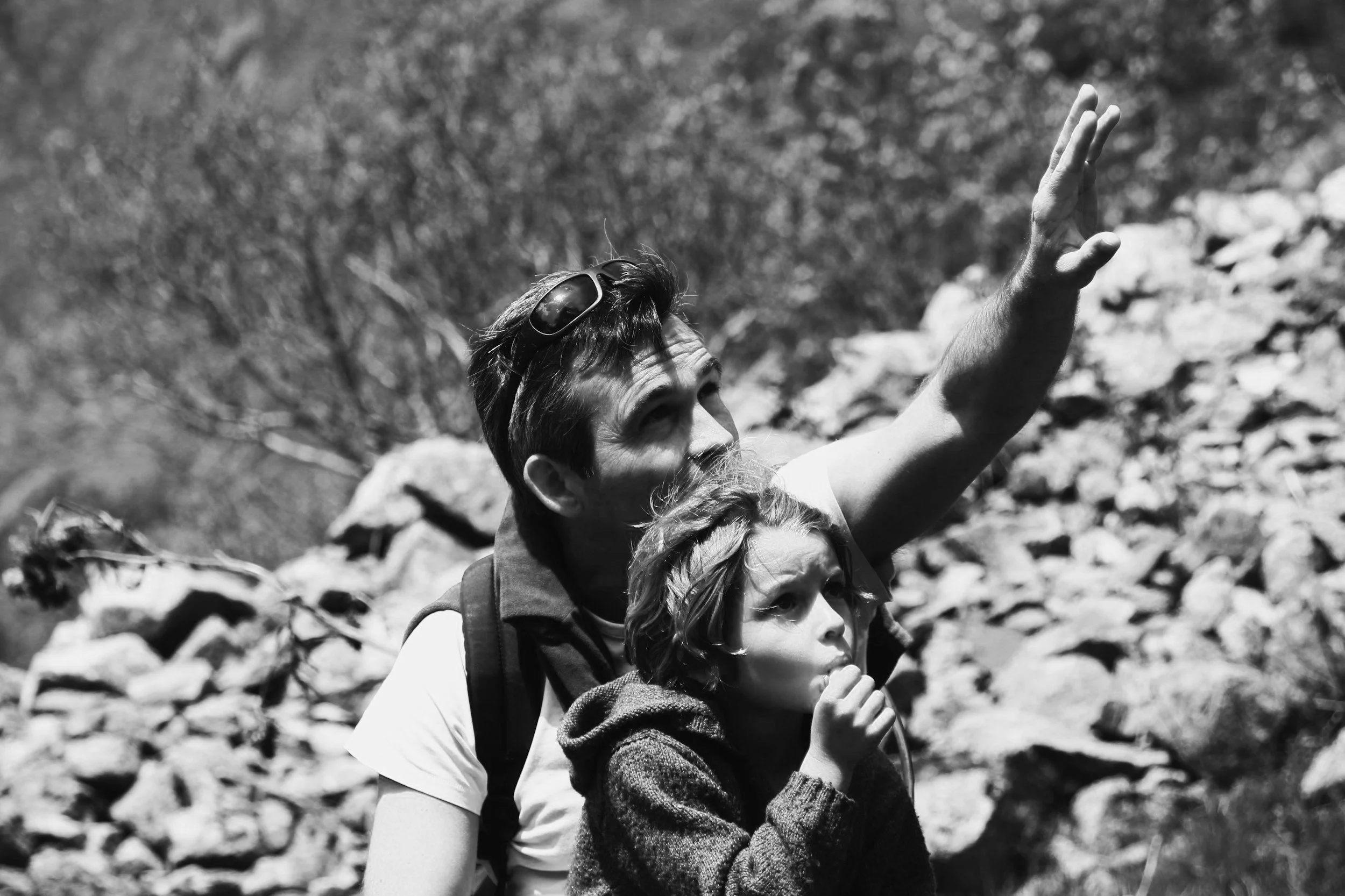 A woman practicing yoga in a studio, performing a forward bend with hands on the floor, in black and white.
