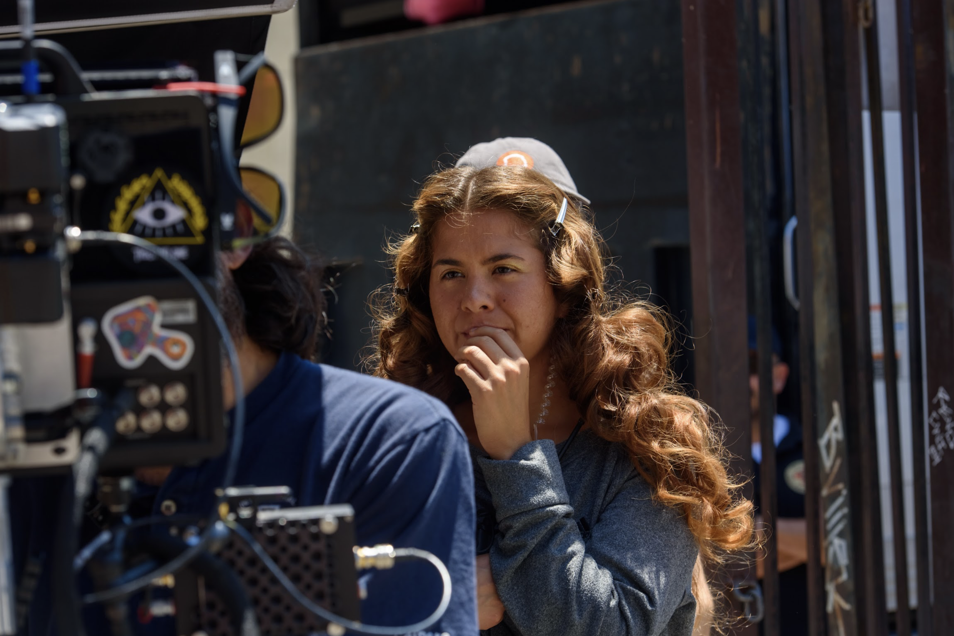 Woman with curly hair and a hair clip selfies behind the camera during a photoshoot.